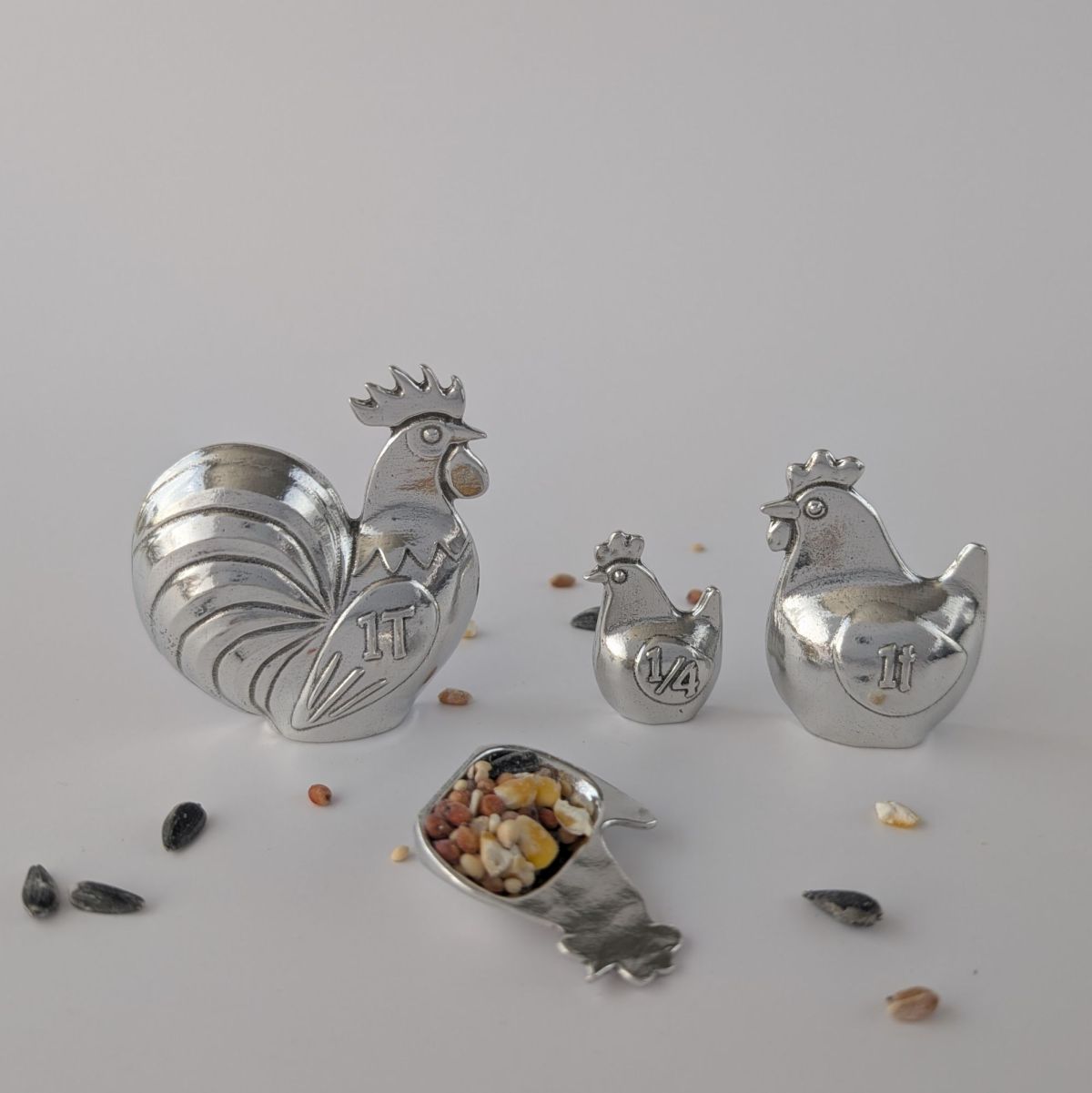 Rooster and hen shaped measuring spoons on a grey background
