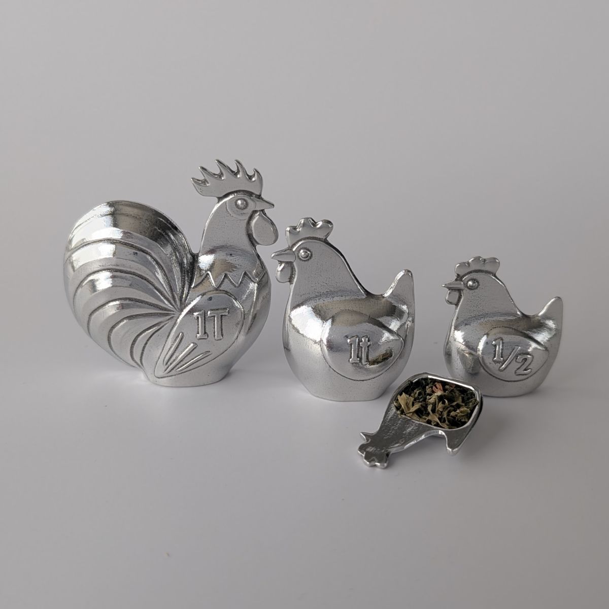 Rooster and hen shaped measuring spoons on a grey background