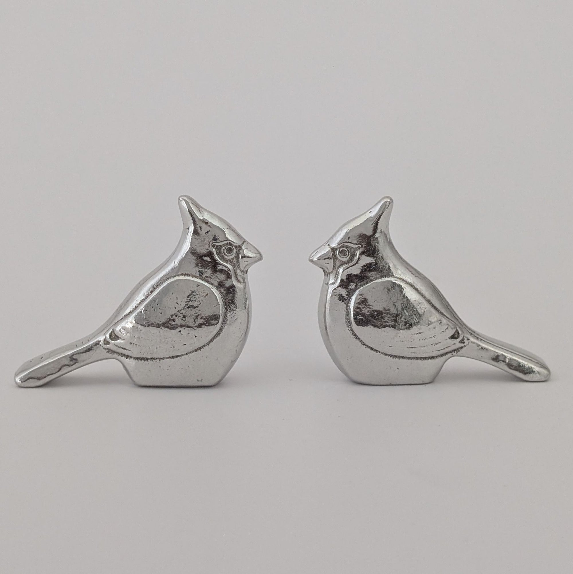 Pair of silver bird-shaped earrings on a light gray background