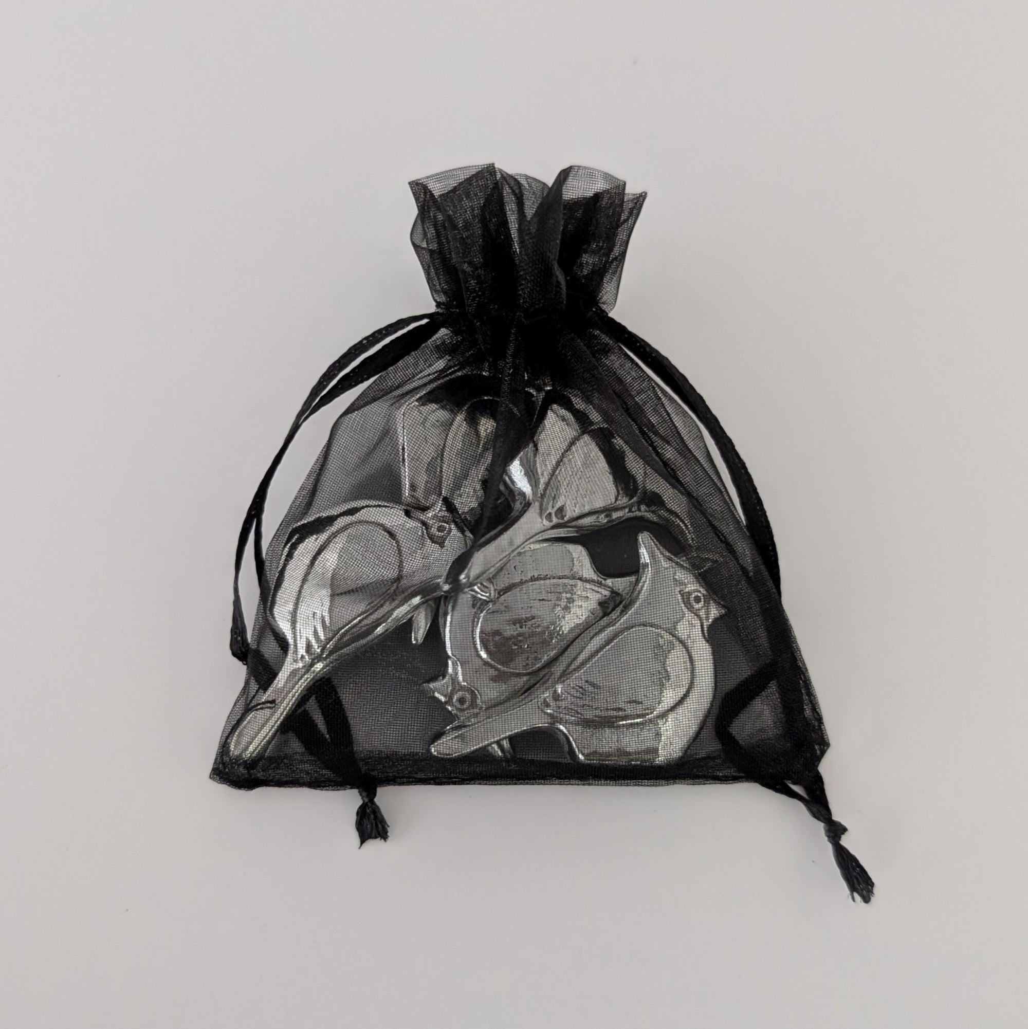 Black drawstring bag with silver birds on a light gray background
