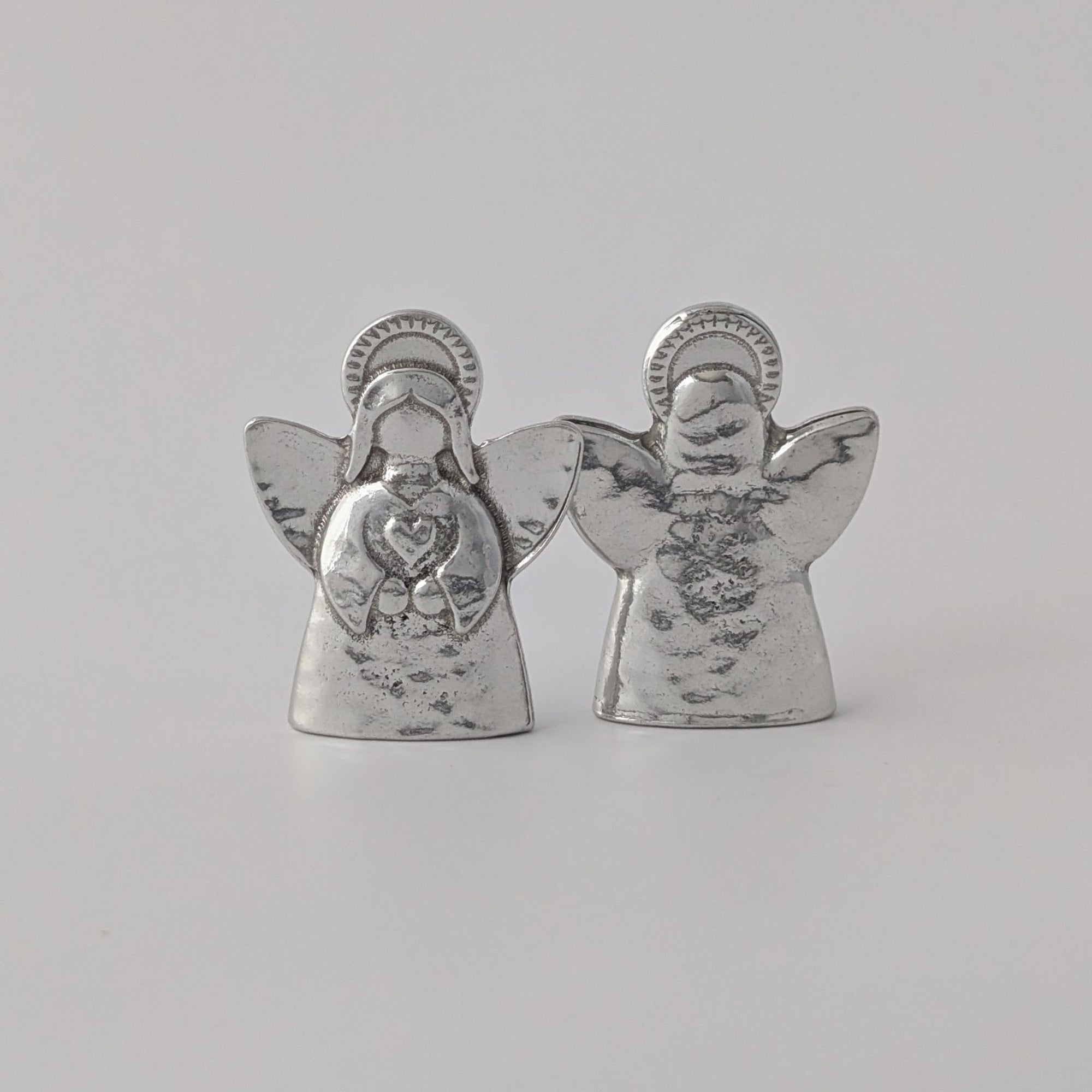 Pair of silver angel figurines on a light gray background