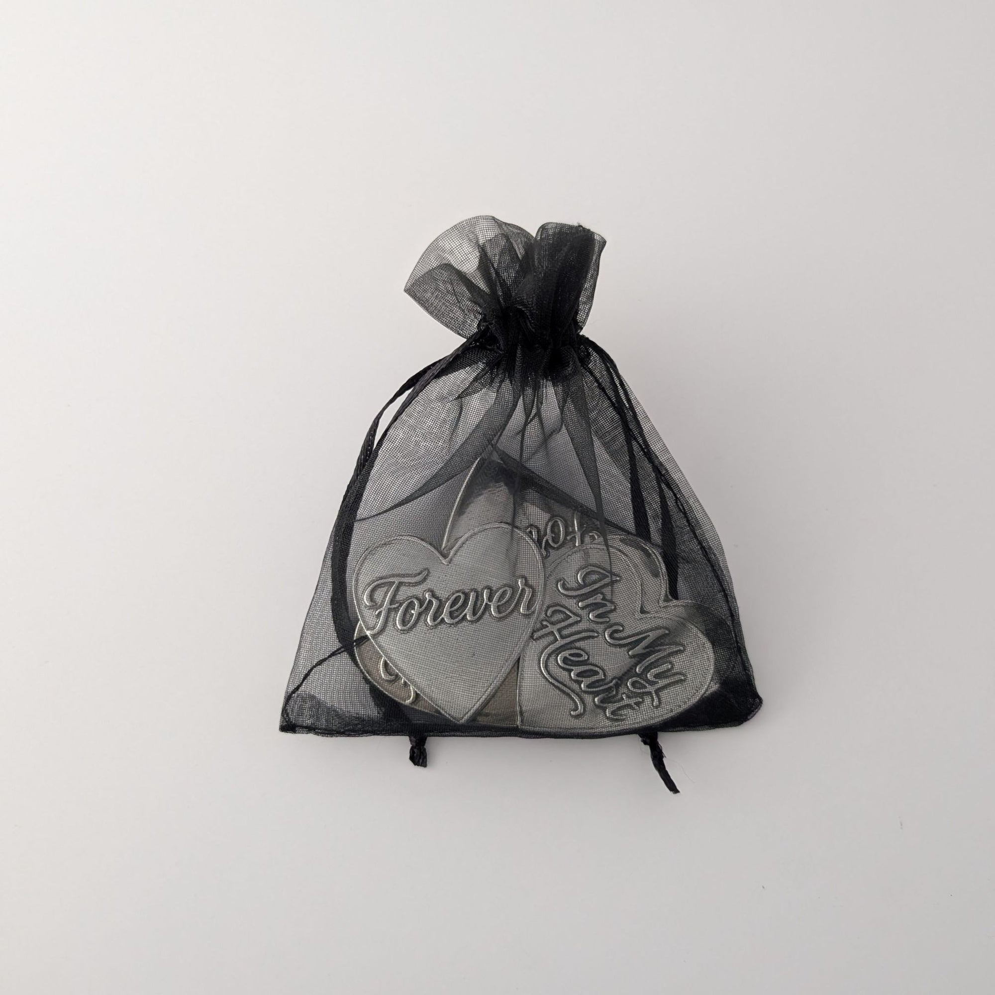 Black drawstring bag with heart-shaped objects inside on a white background