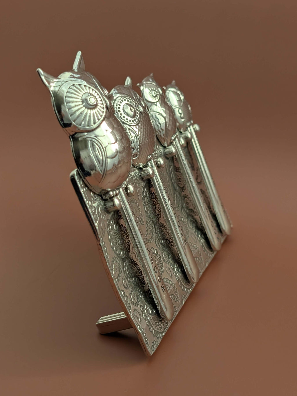 Pewter owl measuring spoons on brown background