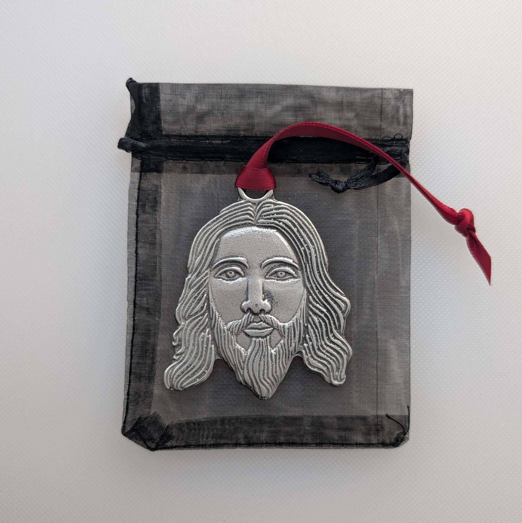 Silver face design on a black drawstring bag with a red string.