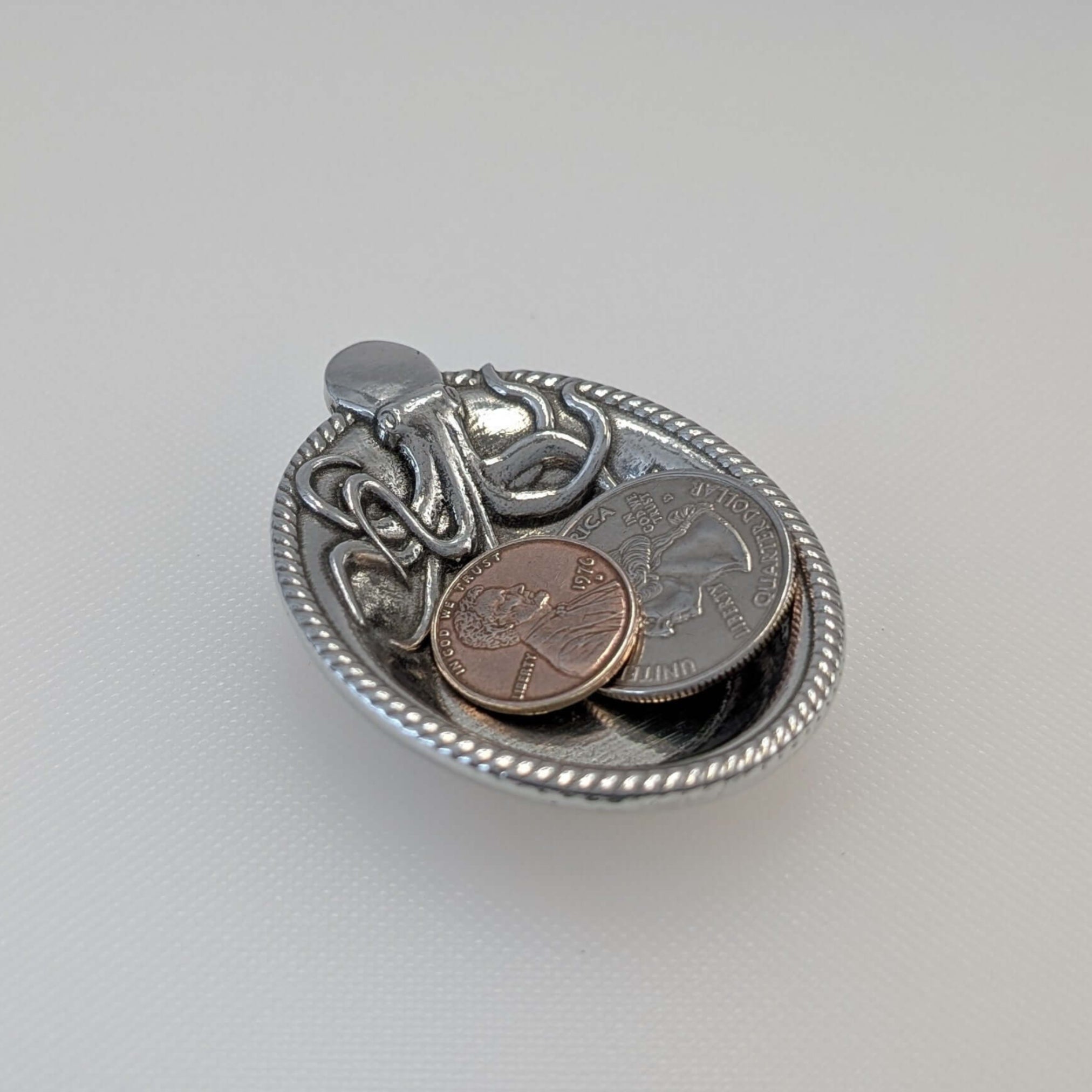 Pewter Octopus ring dish with coins on white surface