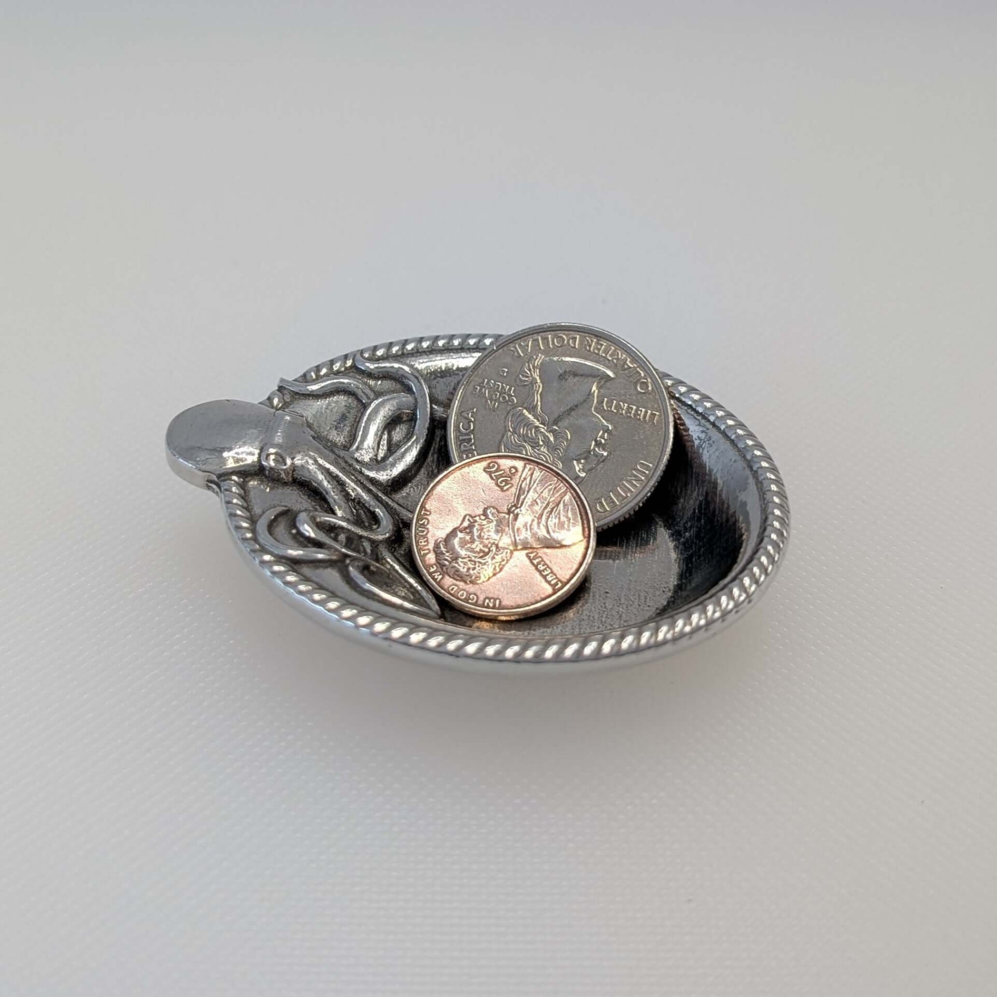 Pewter Octopus ring dish with coins on white surface