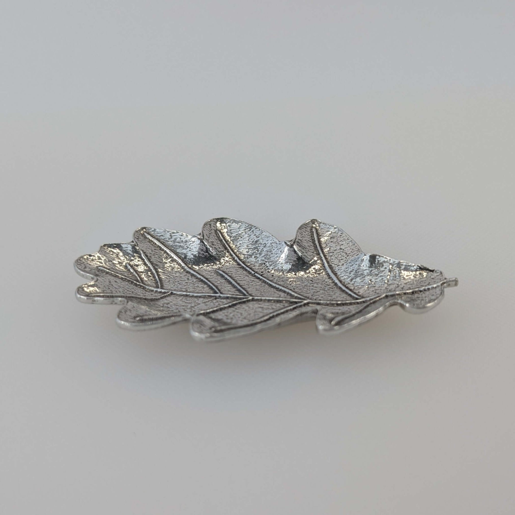 Pewter oak leaf ring dish on white surface