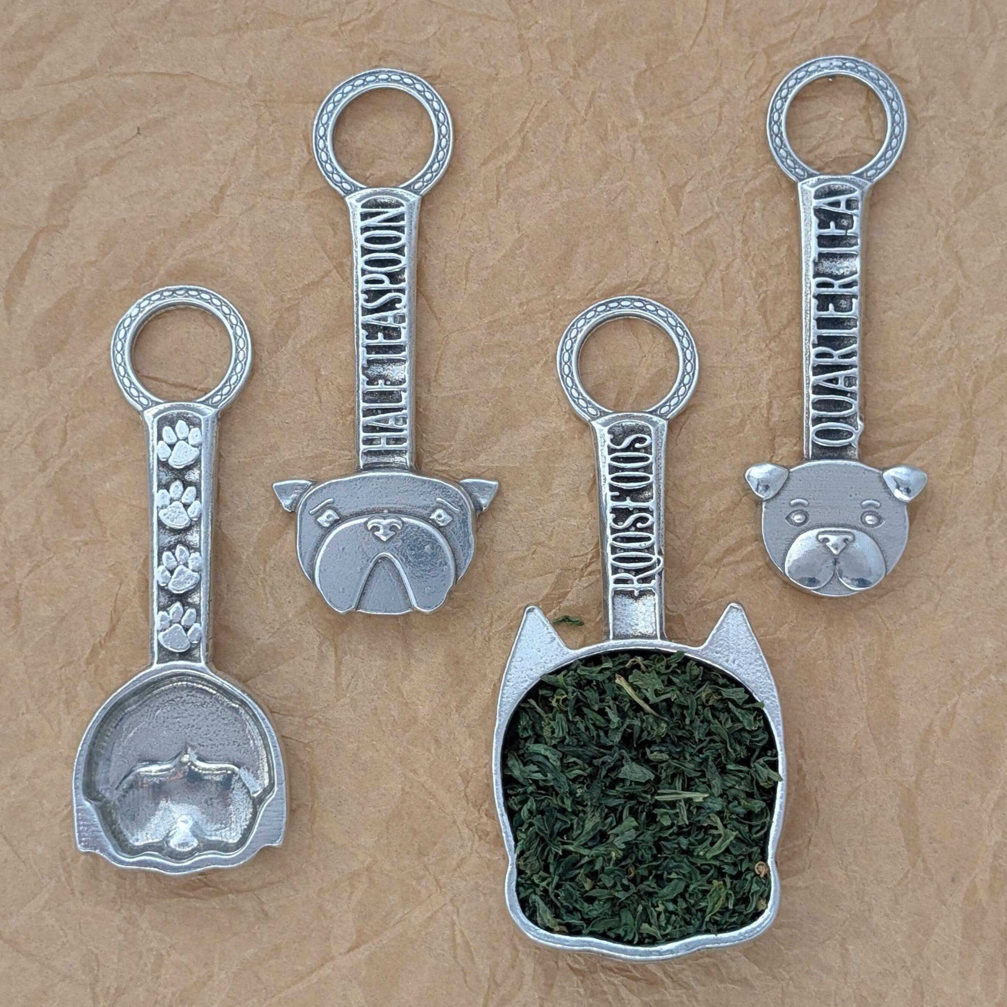 Pewter dog measuring spoons on brown surface