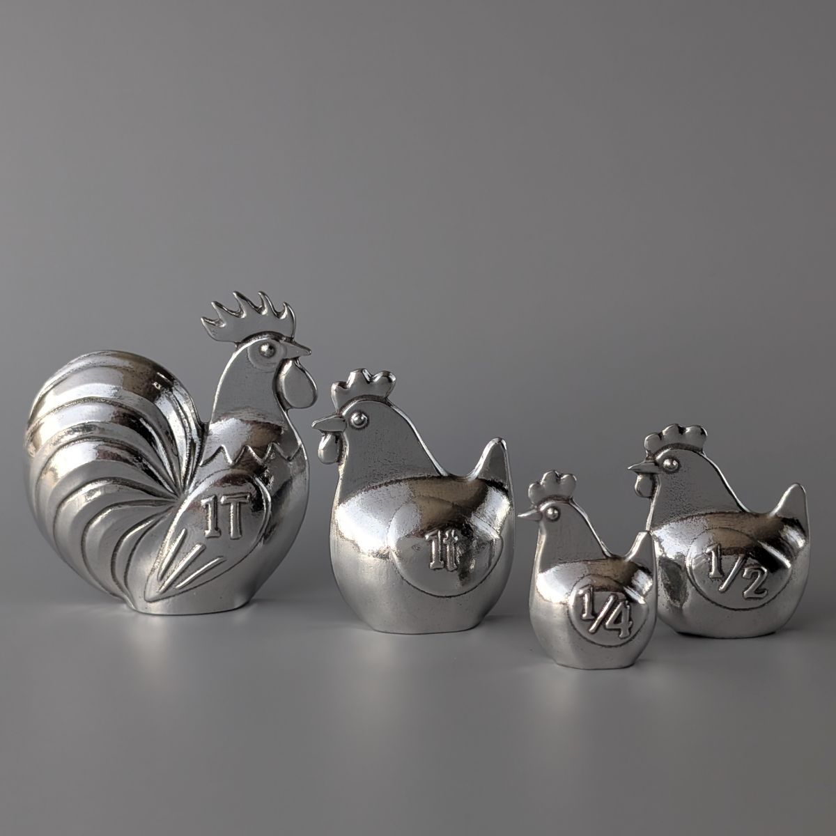 Rooster and hen shaped measuring spoons on a grey background