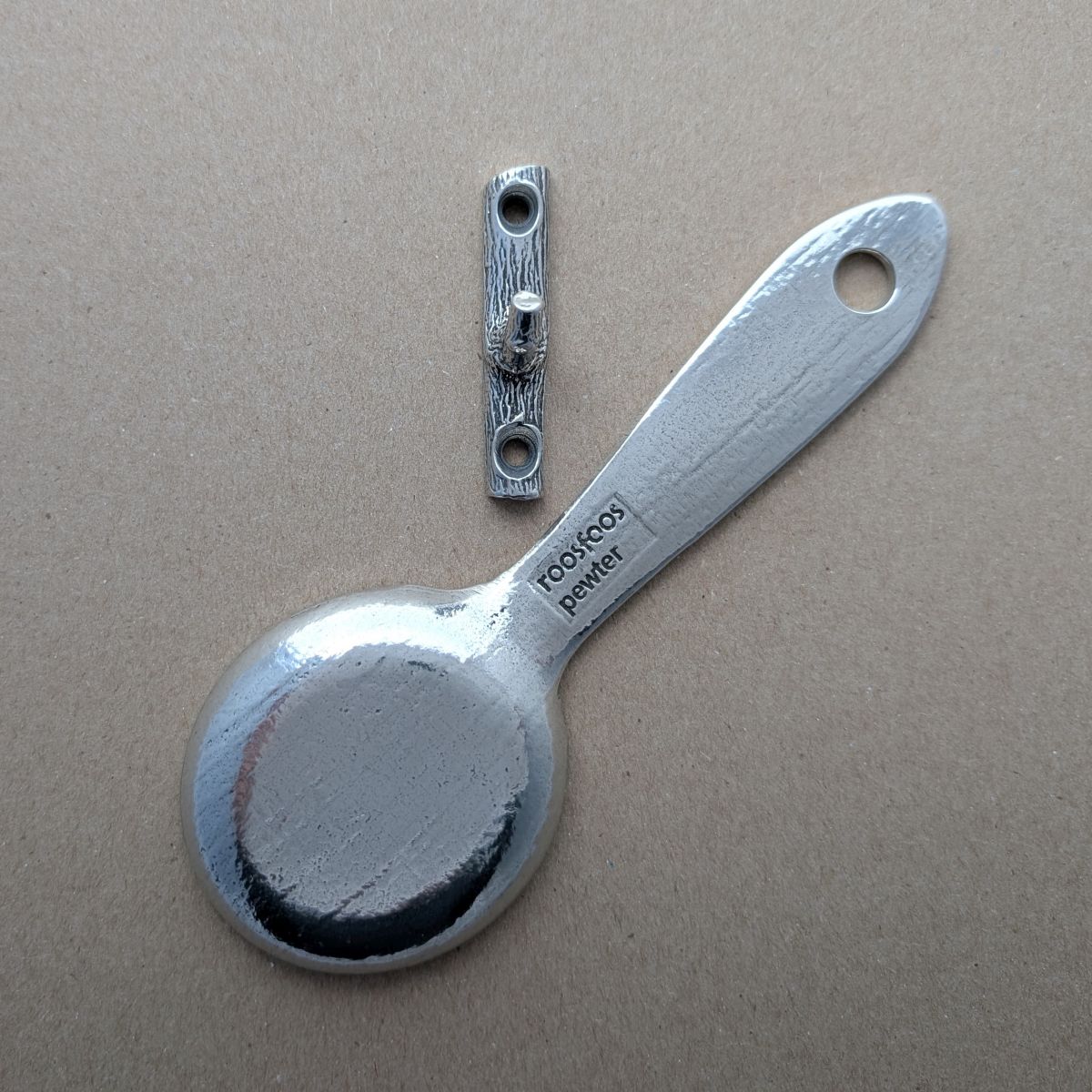 Pewter coffee scoop with coffee and branch hook on brown background
