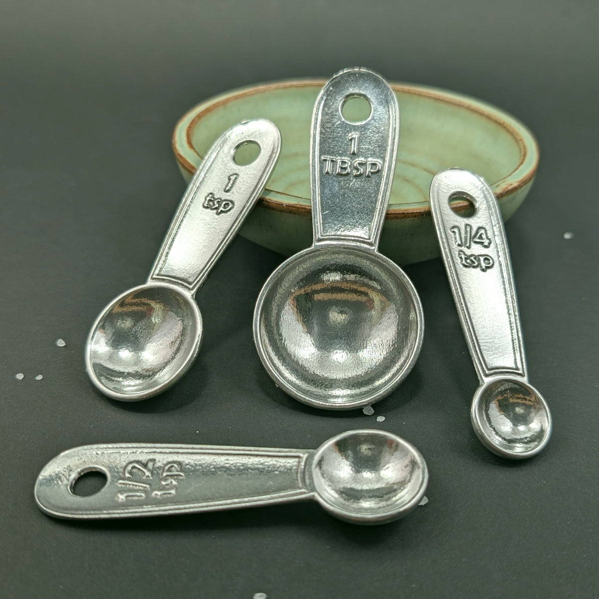 Set of silver measuring spoons on a dark surface