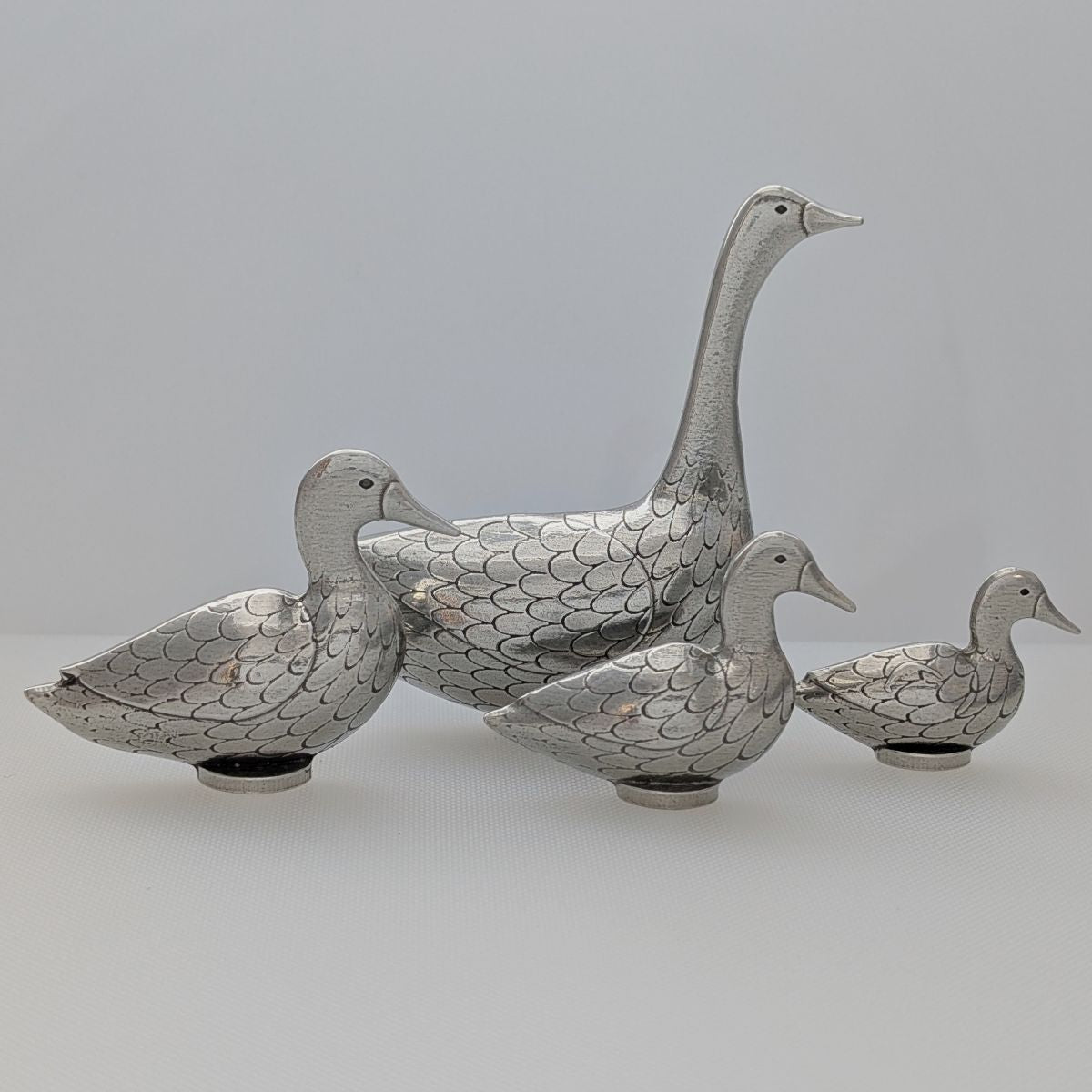 Pewter goose and duck measuring spoons on blue background