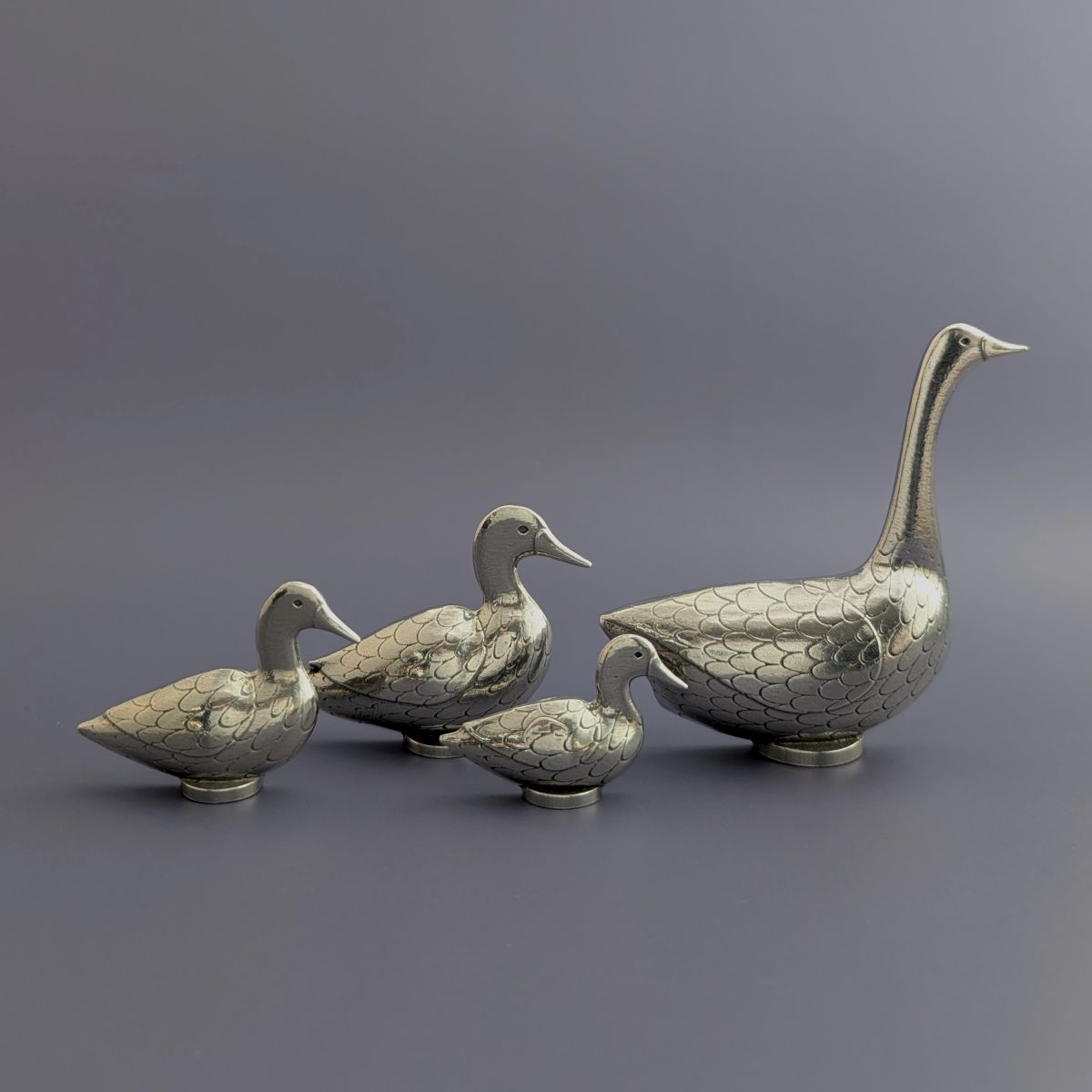 Pewter goose and duck measuring spoons on blue background