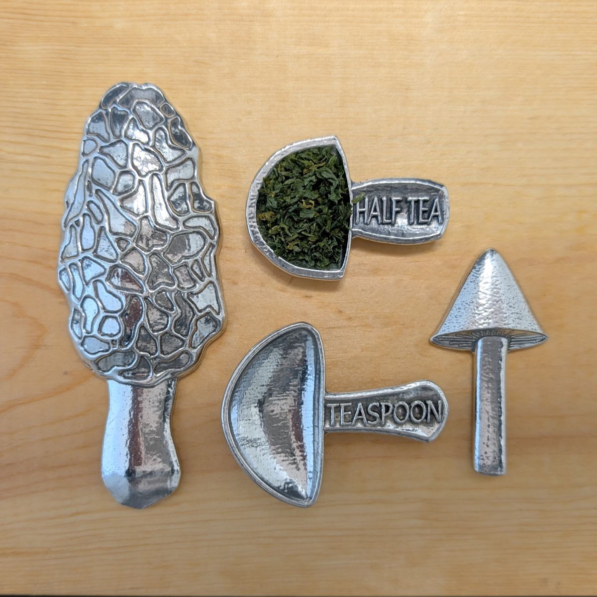 Pewter mushroom measuring spoons on wooden surface 