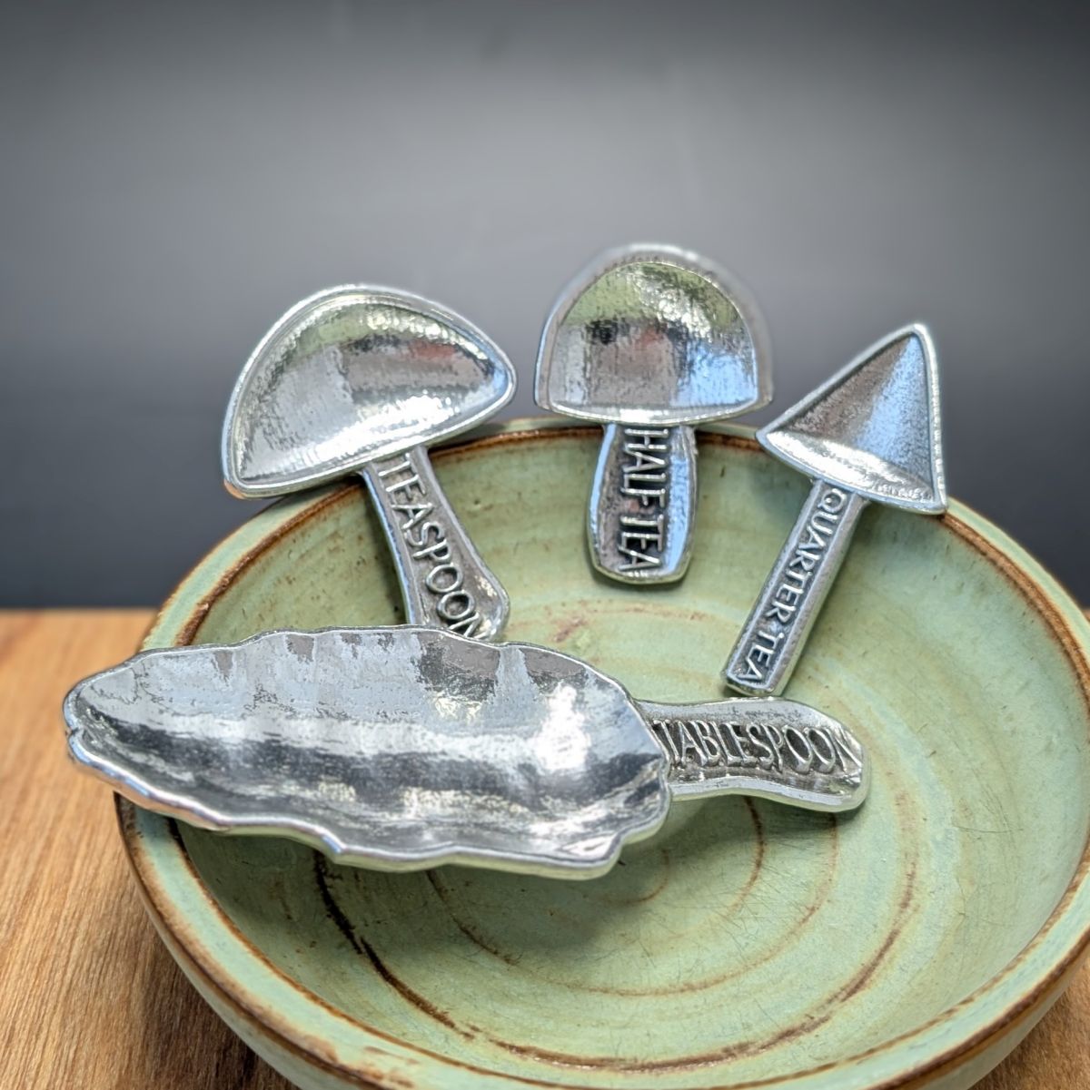 Pewter mushroom measuring spoons in a green bowl