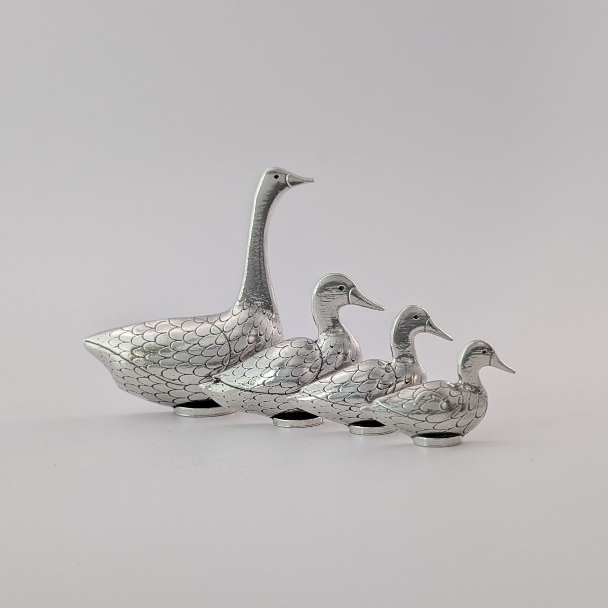 Pewter goose and duck measuring spoons on greay background