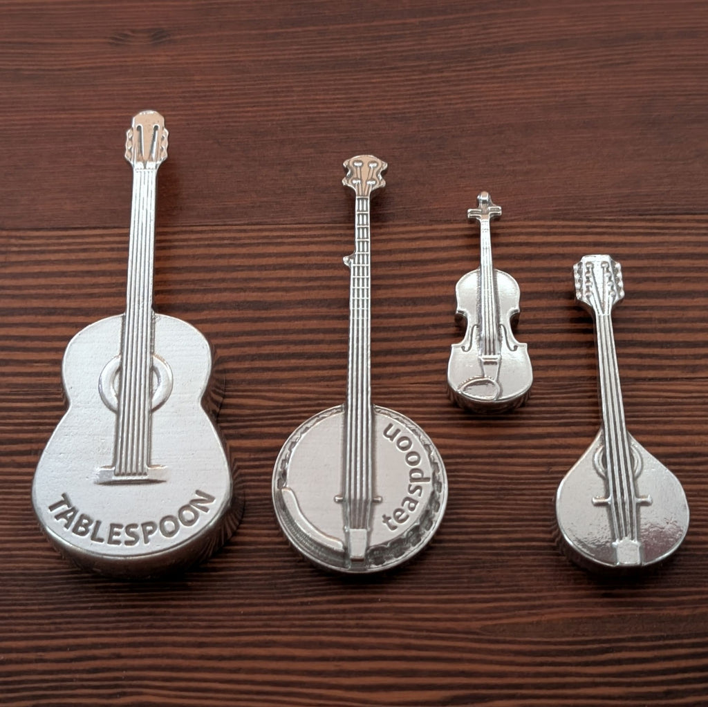 Set of silver musical instrument-shaped spoons on a wooden surface