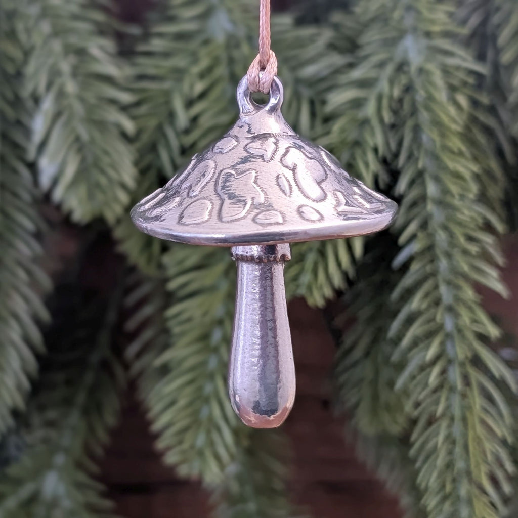 Silver mushroom ornament hanging against a green leafy background