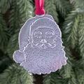 Silver Santa Claus ornament with a red ribbon on a Christmas tree.