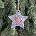 Star-shaped ornament with a heart in the center hanging against a green leafy background