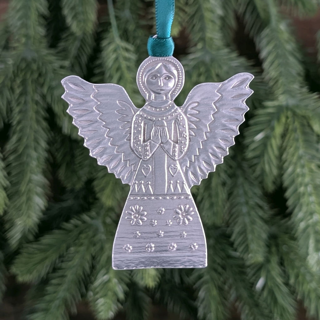 Silver angel ornament with a blue ribbon on a Christmas tree.
