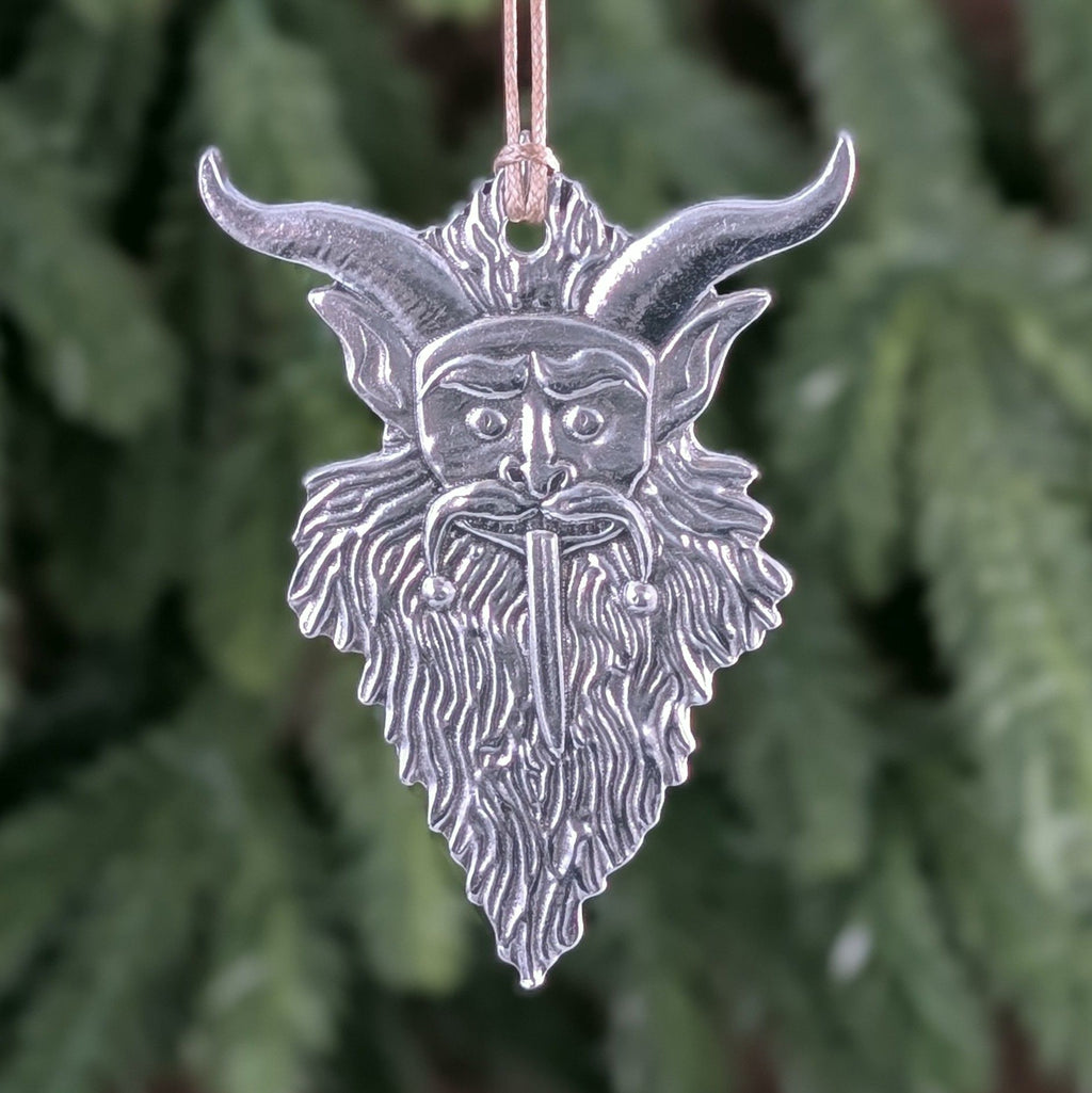 Silver goat head ornament with horns against a blurred green background