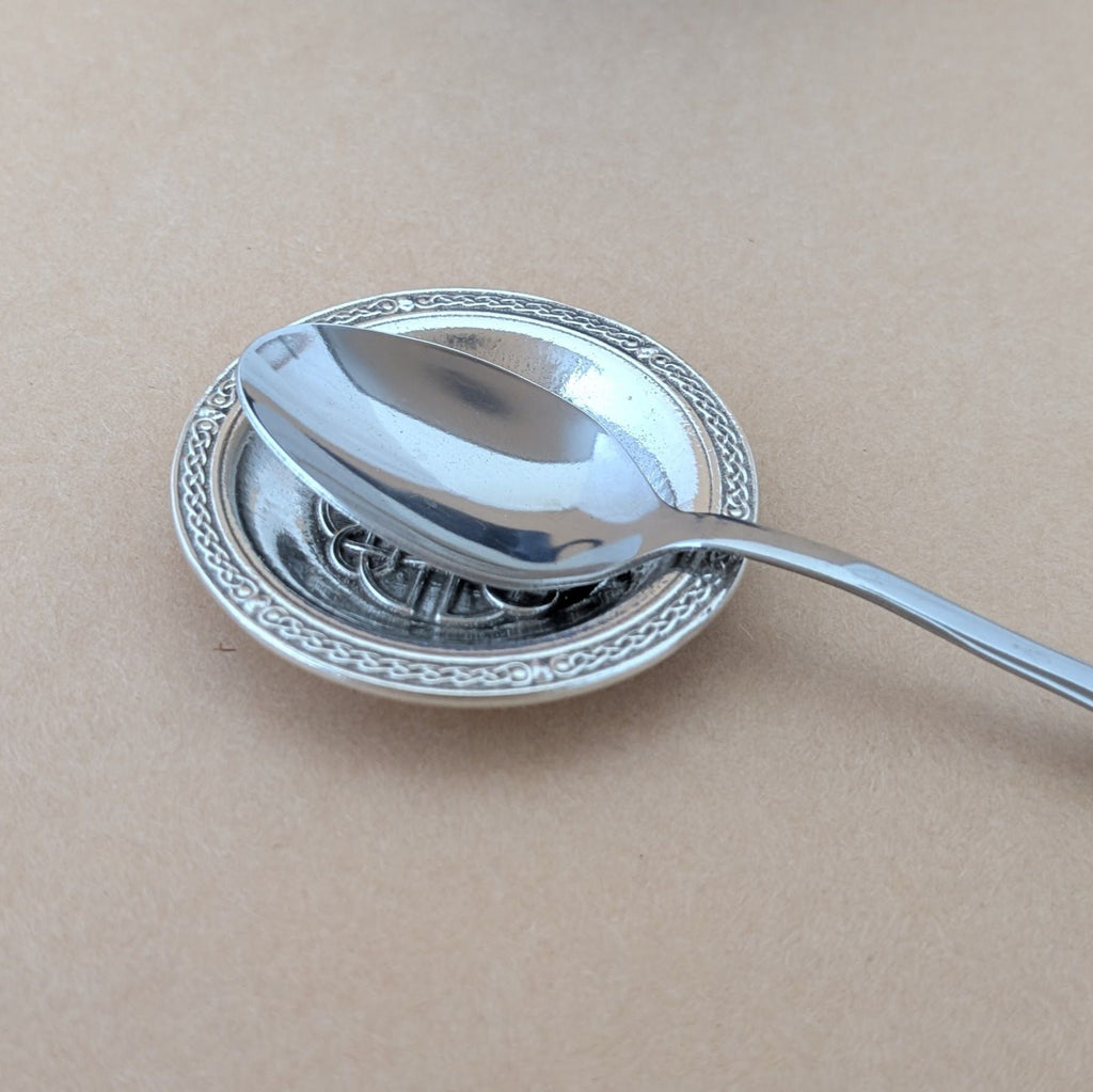 Silver spoon with decorative bowl on a beige background