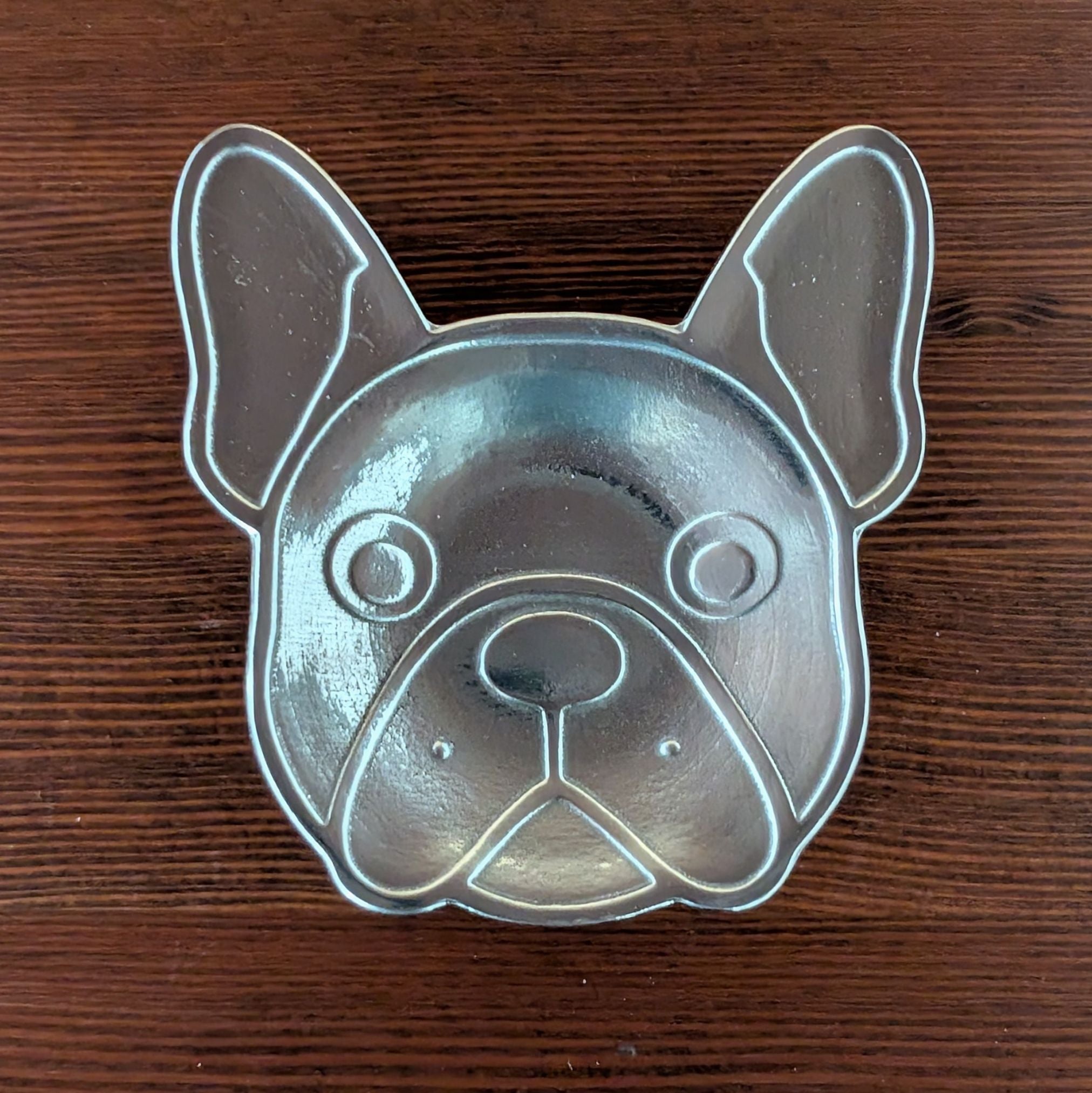 Metallic dog-shaped dish on a wooden surface