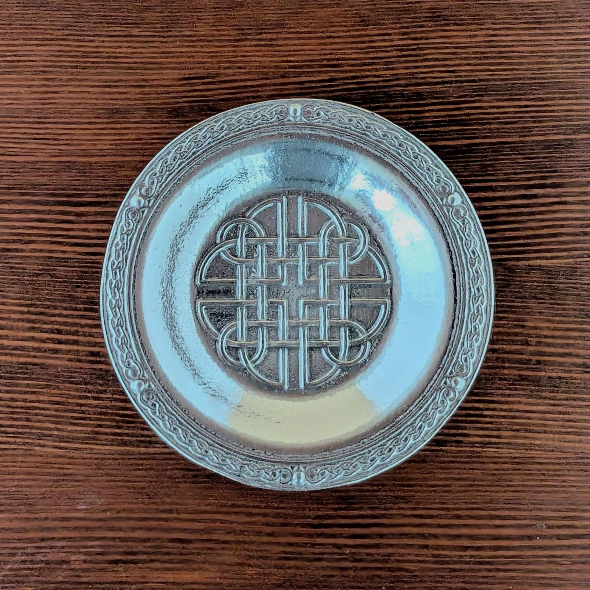 Decorativepewter ring dish with celtic Dara knot on a wooden surface