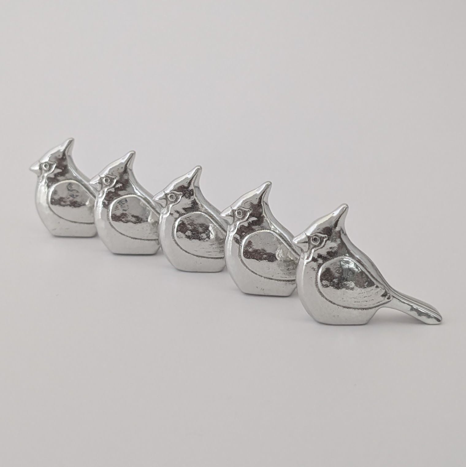 Set of five silver bird-shaped objects on a light gray background