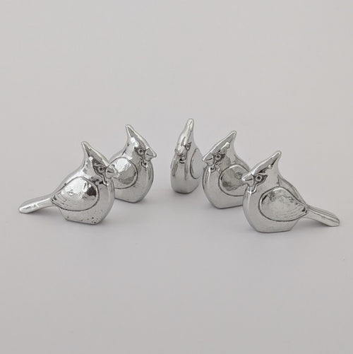 Set of five pewter cardinal keepsake tokens on a light gray background