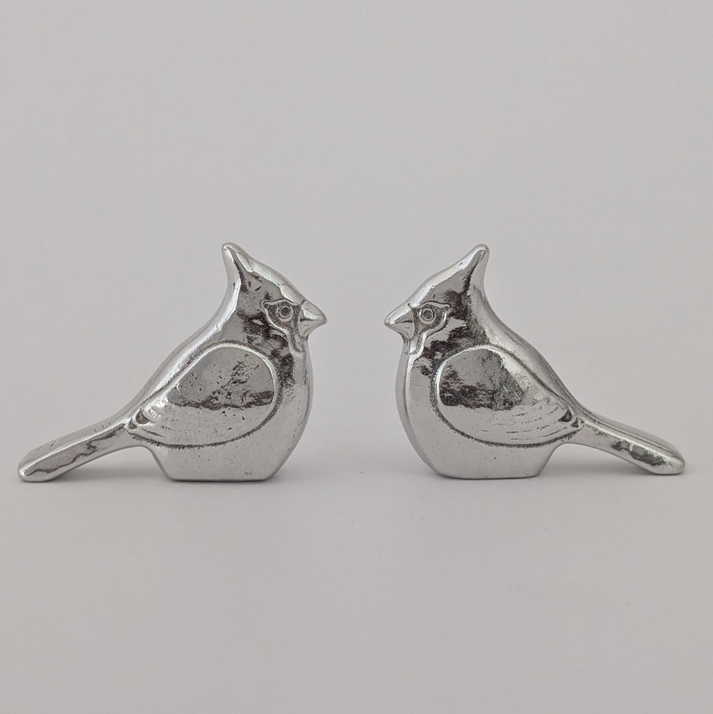 Pair of silver bird-shaped earrings on a light gray background