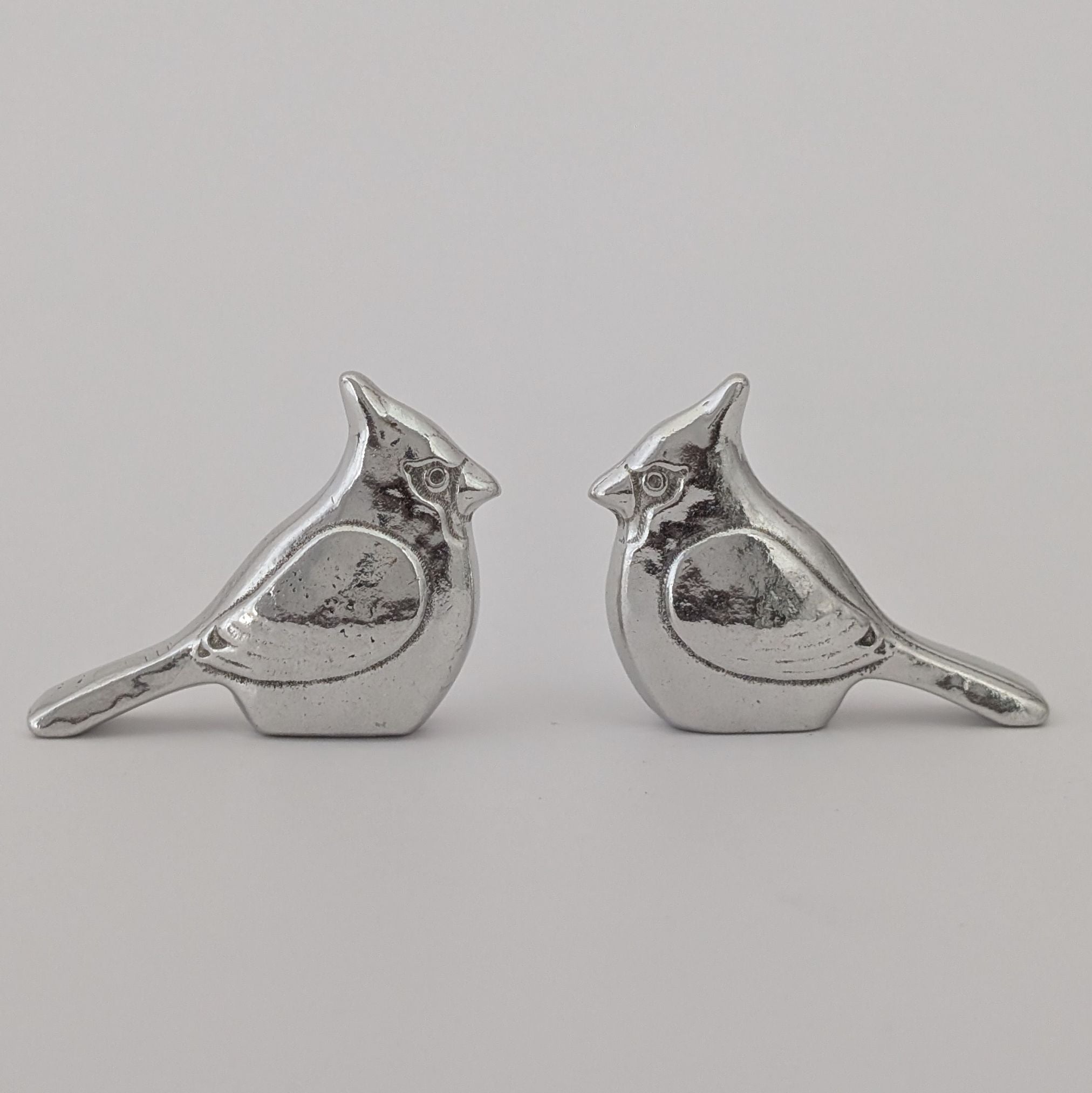 Pair of silver bird-shaped earrings on a light gray background