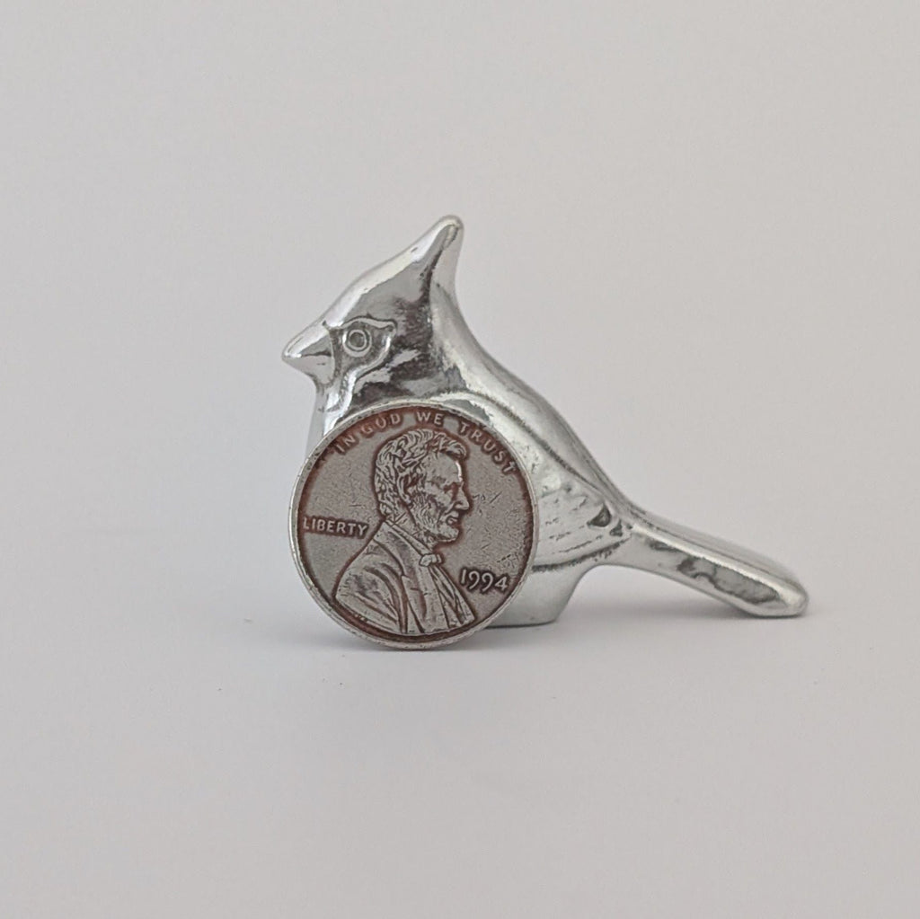 Silver bird-shaped ring with a coin inset on a gray background