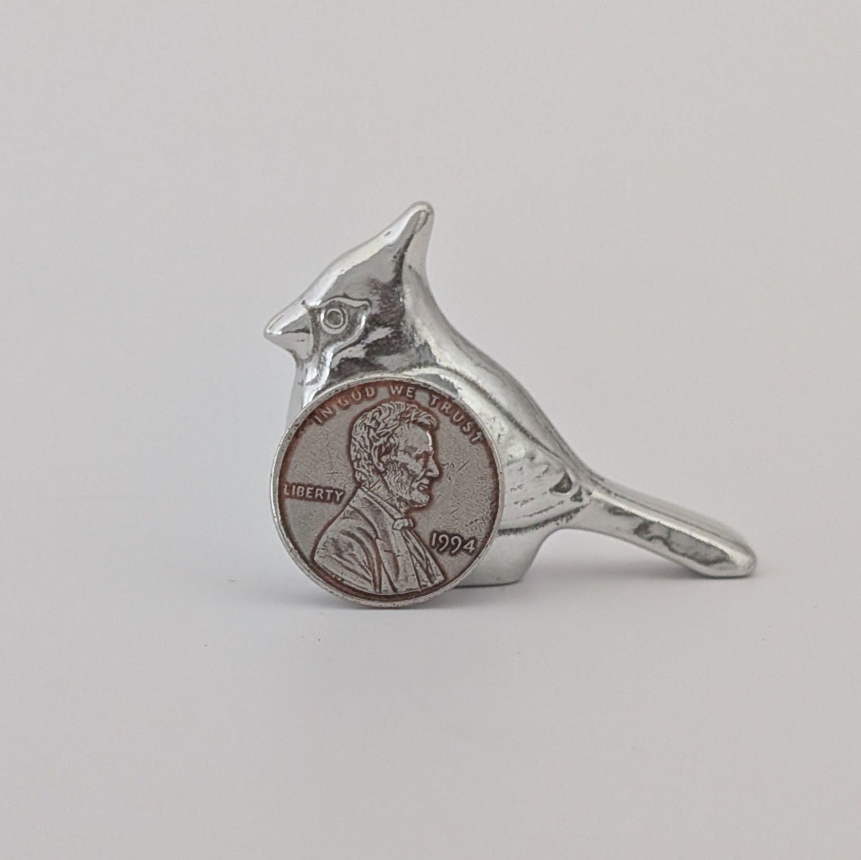 Silver bird-shaped ring with a coin inset on a gray background