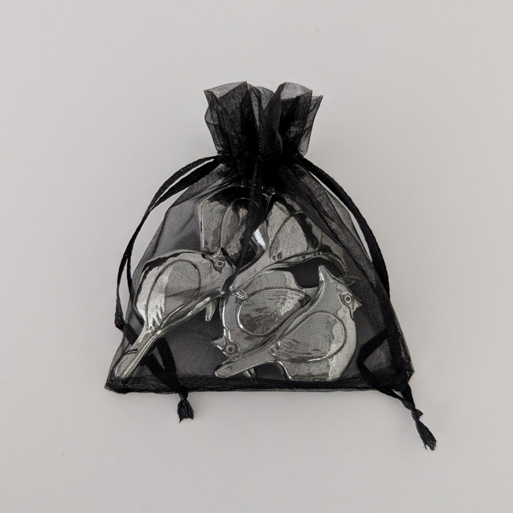 Black drawstring bag with silver birds on a light gray background