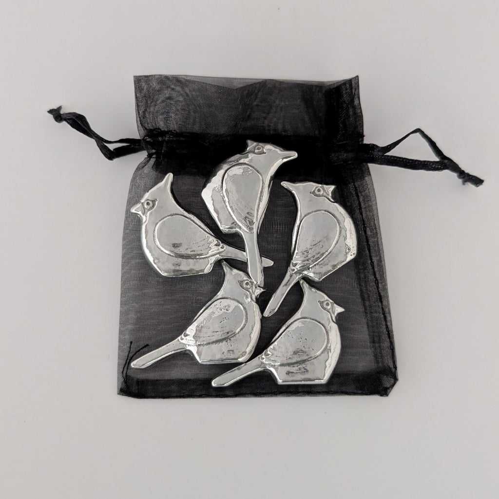 Silver bird-shaped objects in a black drawstring bag on a light gray background