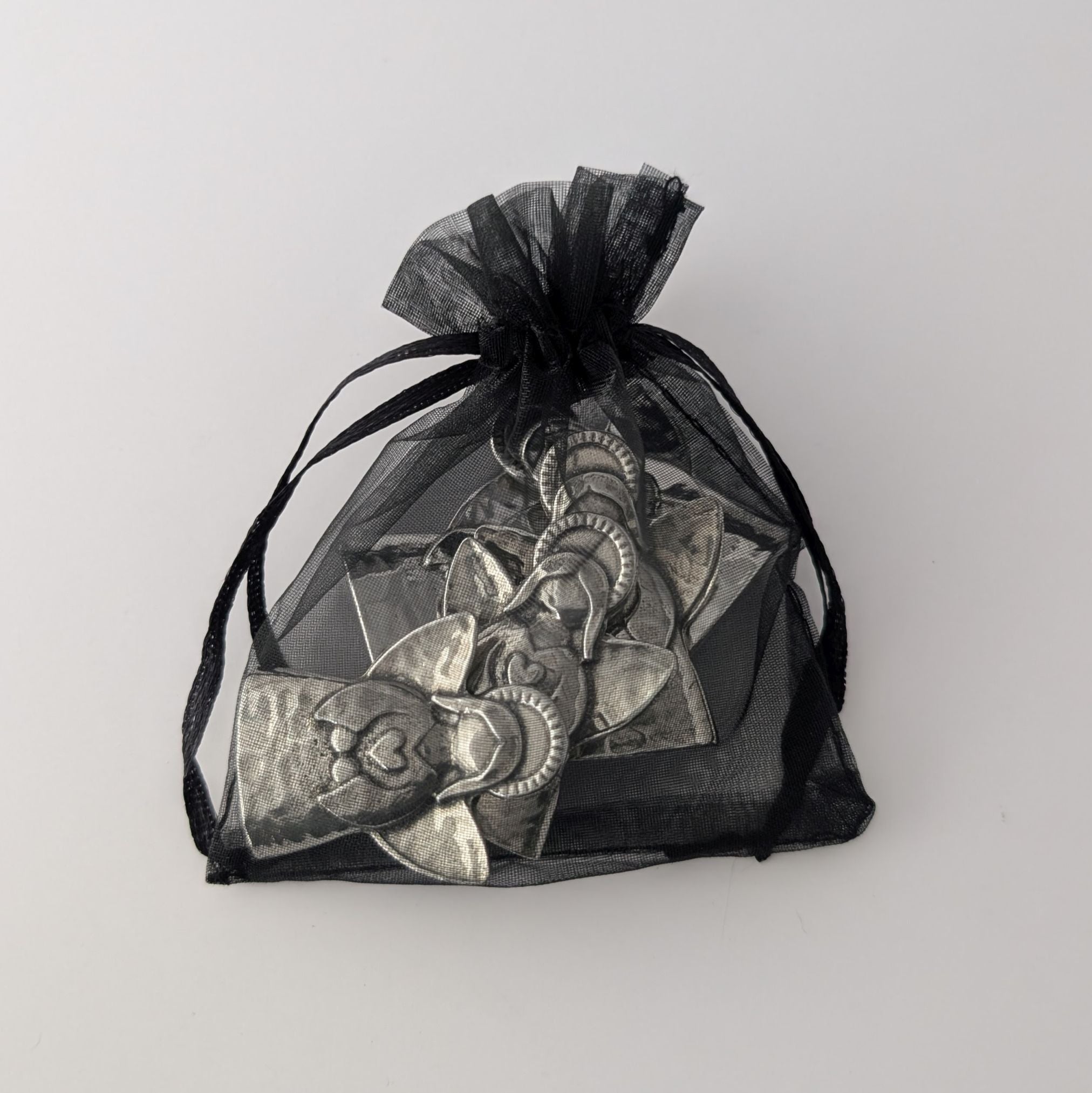 Black drawstring bag with decorative items on a light gray background