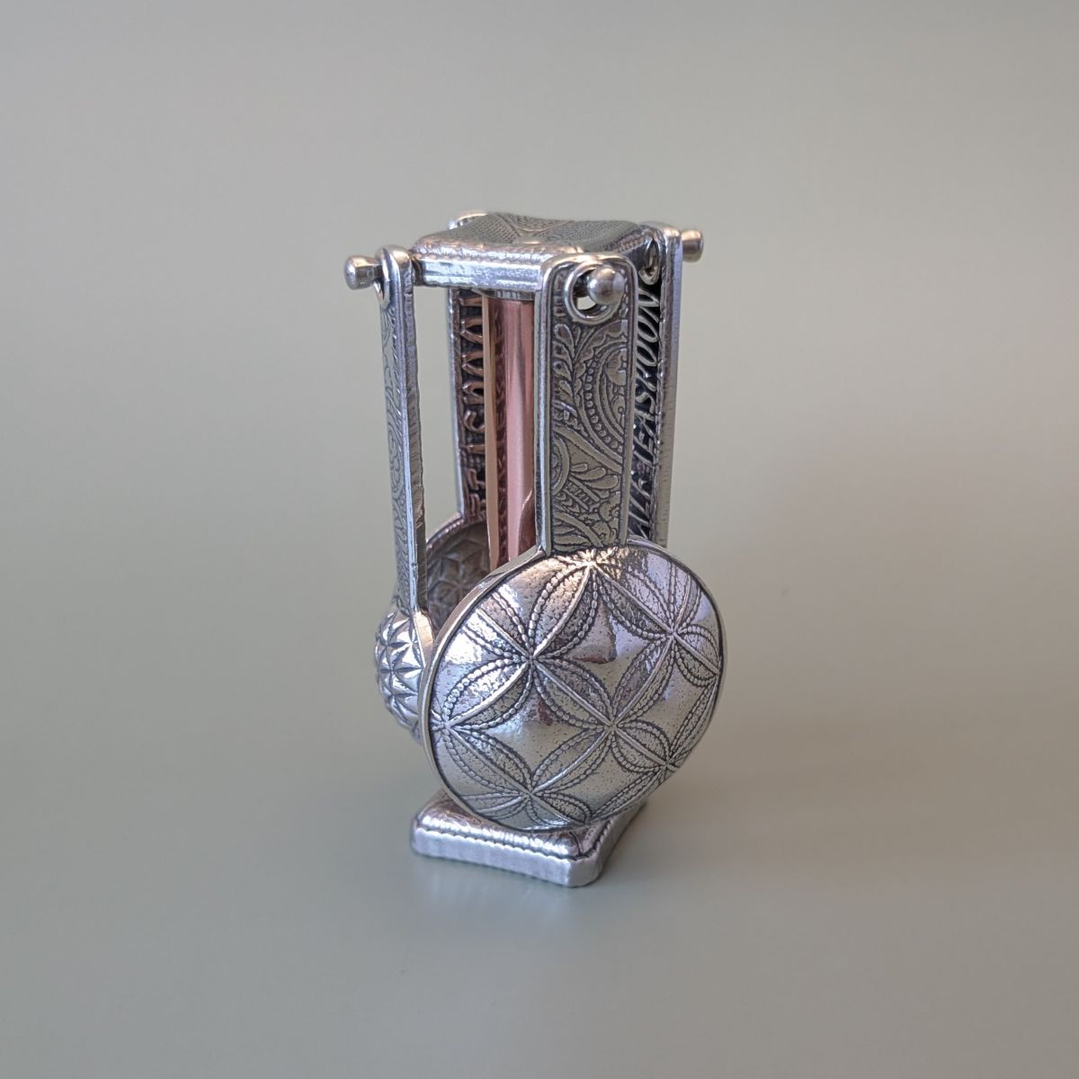 Pewter measuring spoons on copper stand- green background