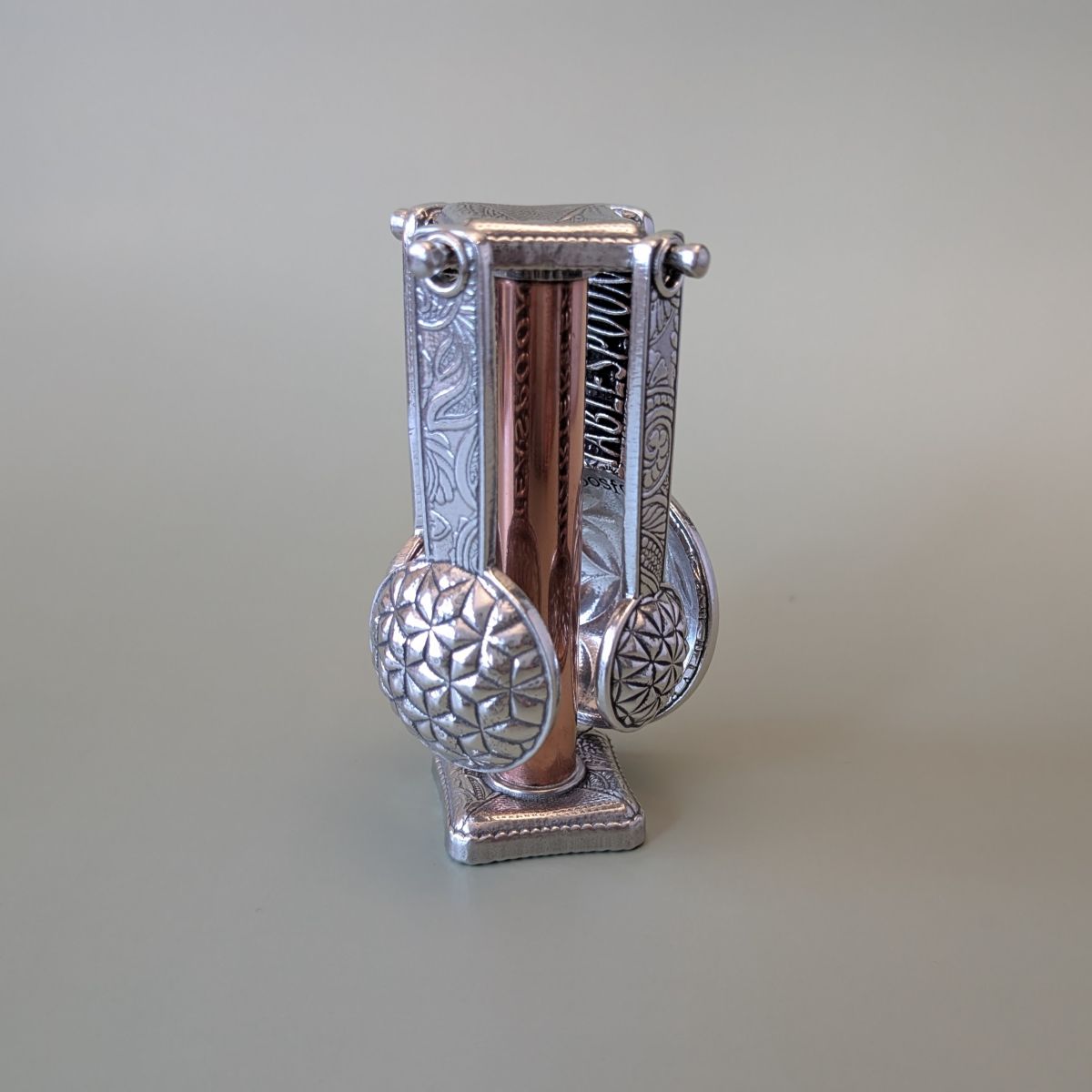 Pewter measuring spoons on copper stand- green background