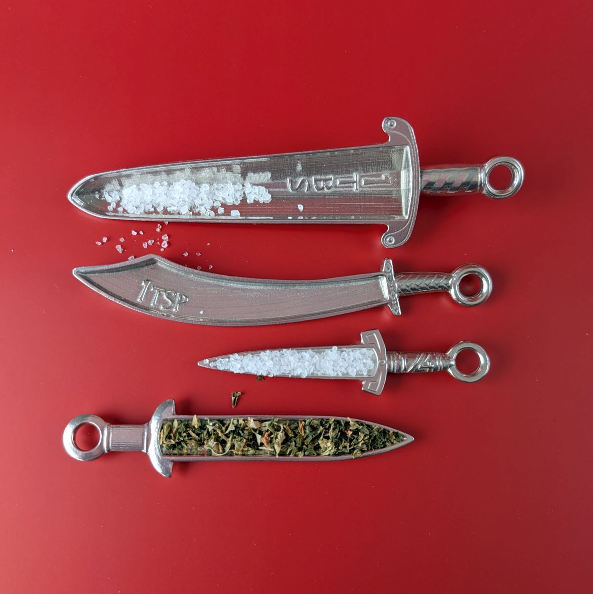 Pewter measuring spoons shaped like swords on red background