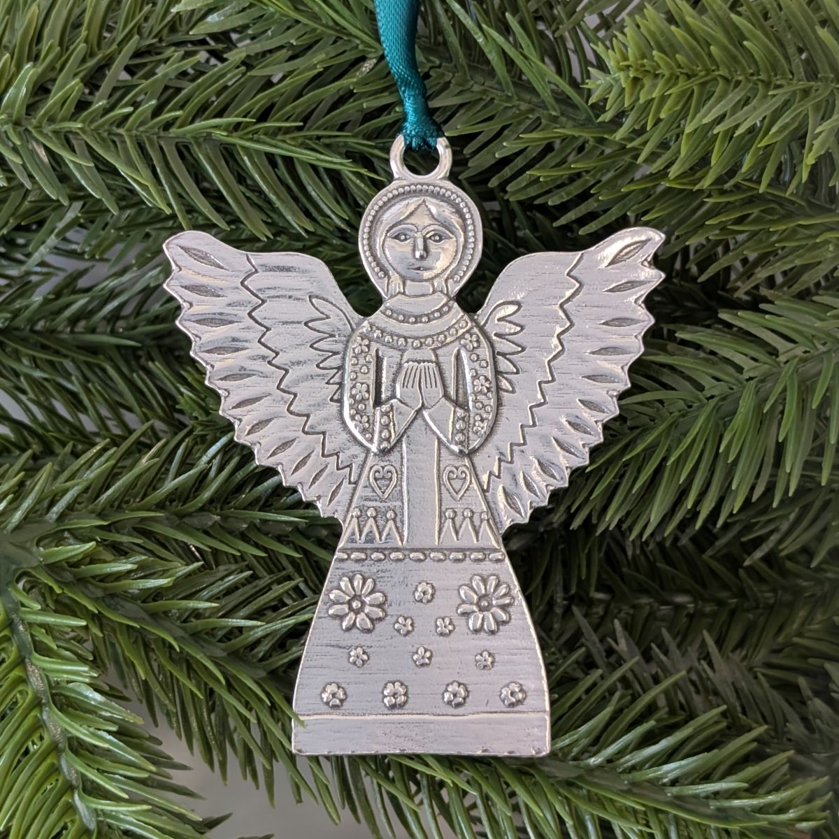 Silver angel ornament on a green pine branch