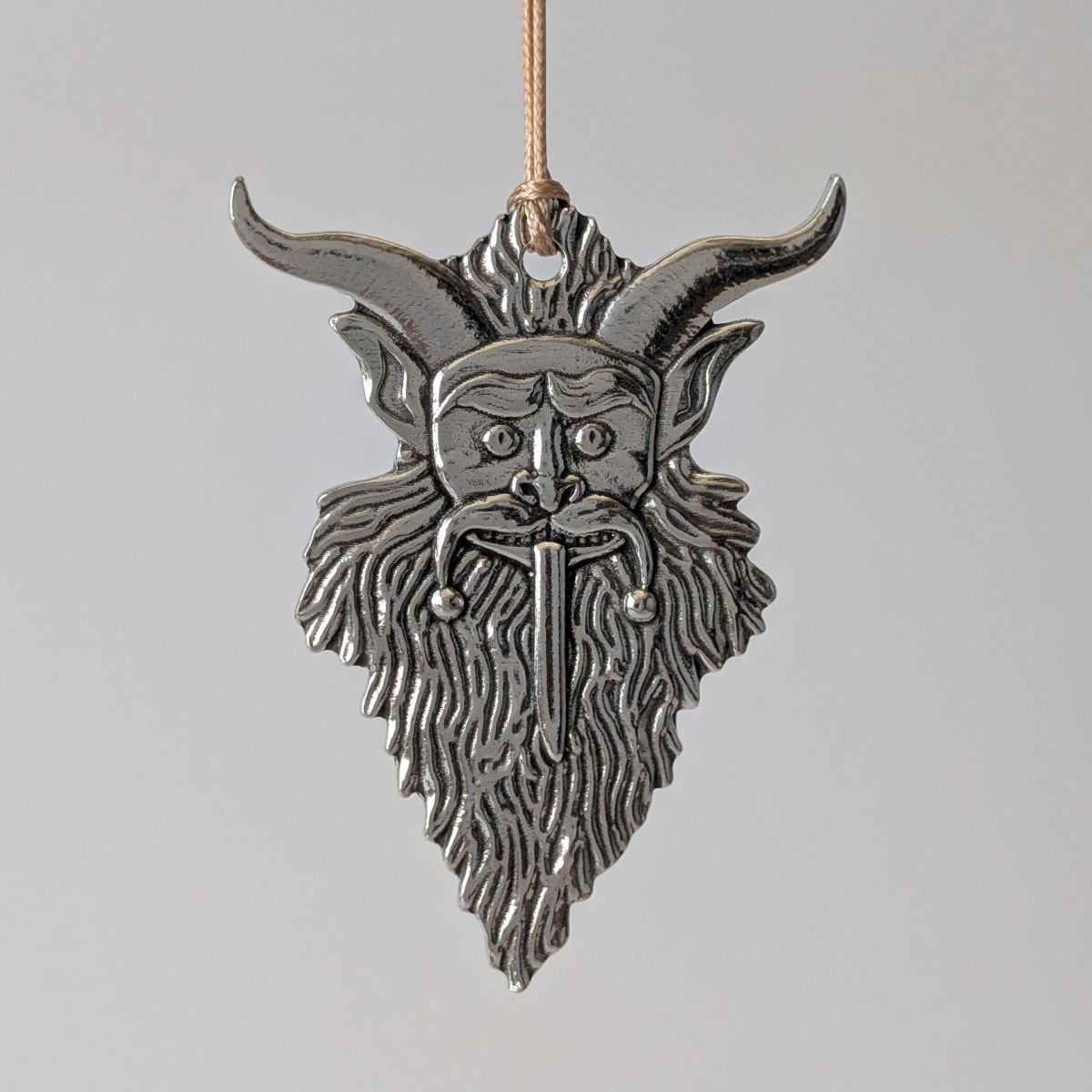 Metallic ornament with a Krampus design on a gray background