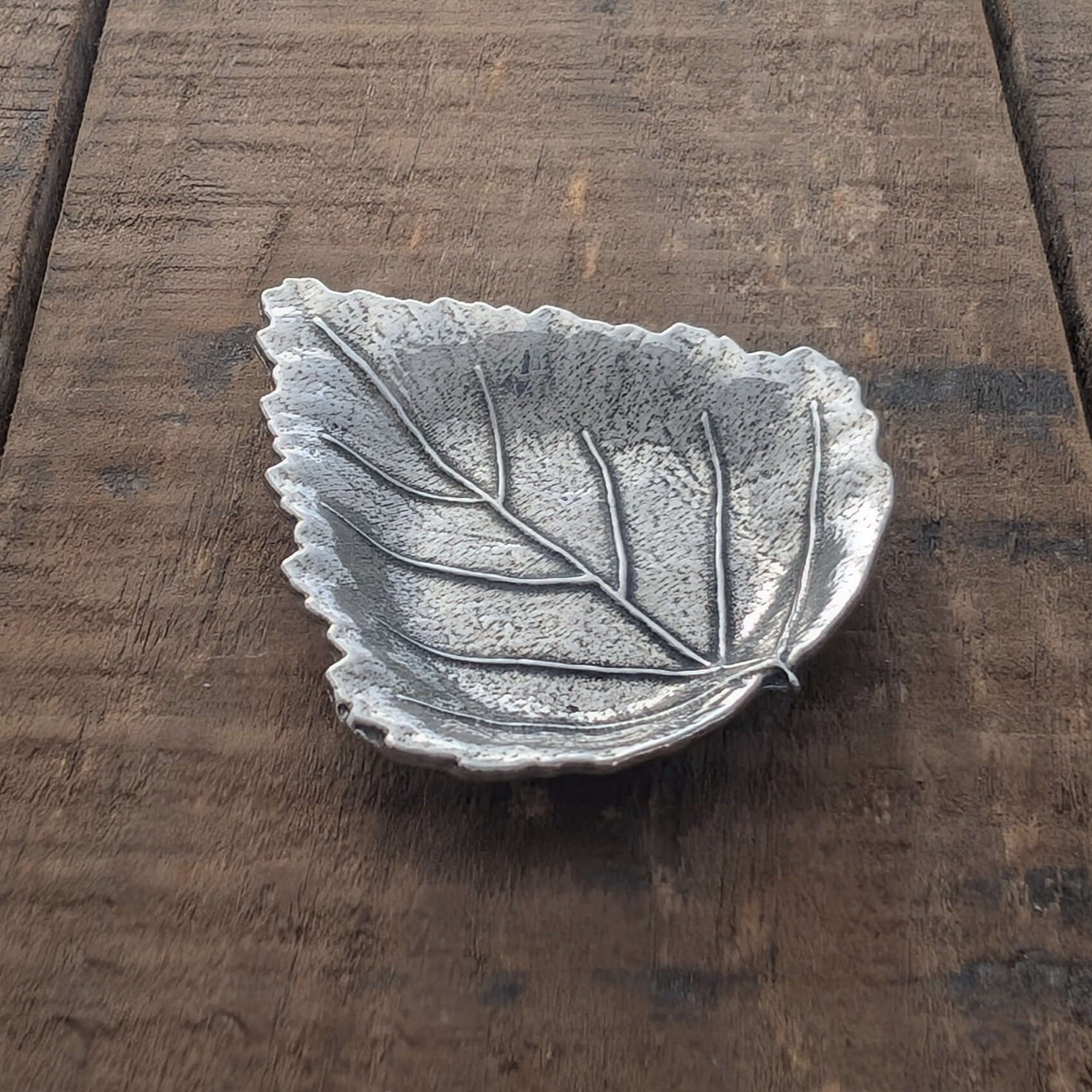 Pewter leaf dish on wood surface