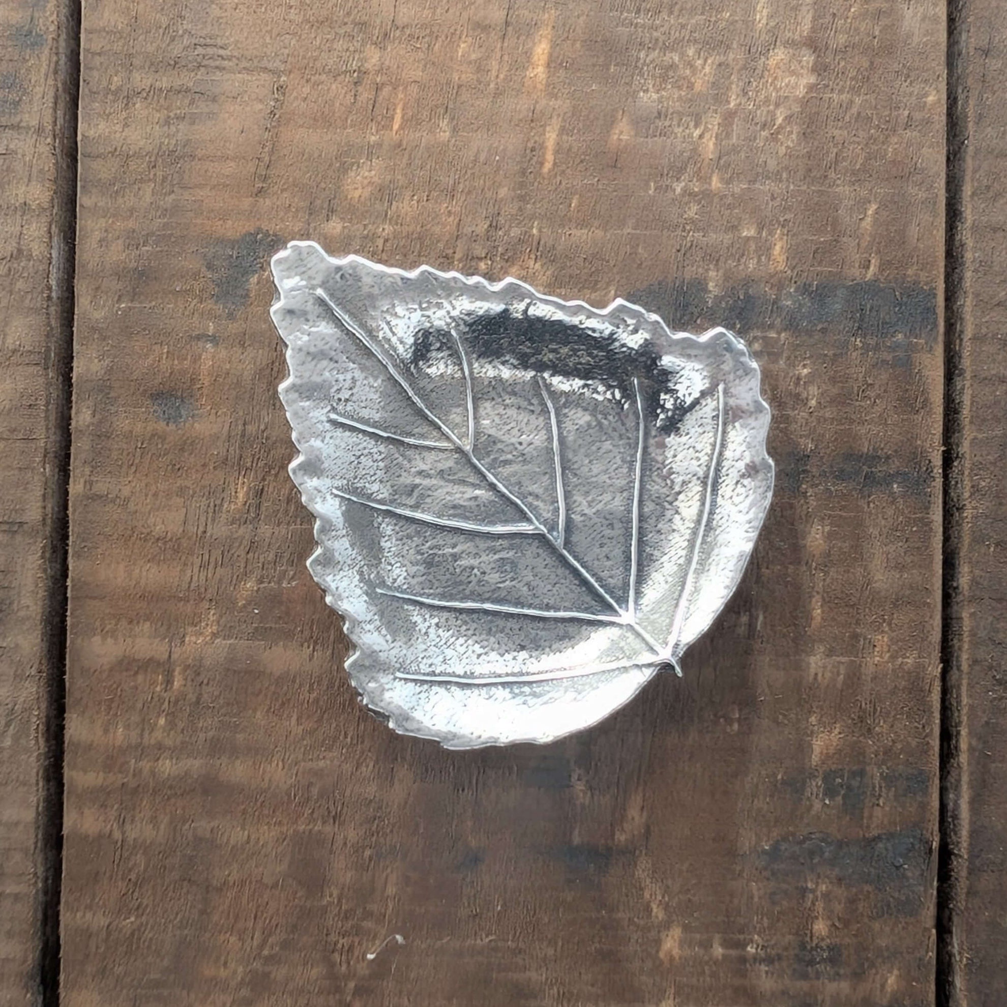 Pewter leaf dish on wood surface