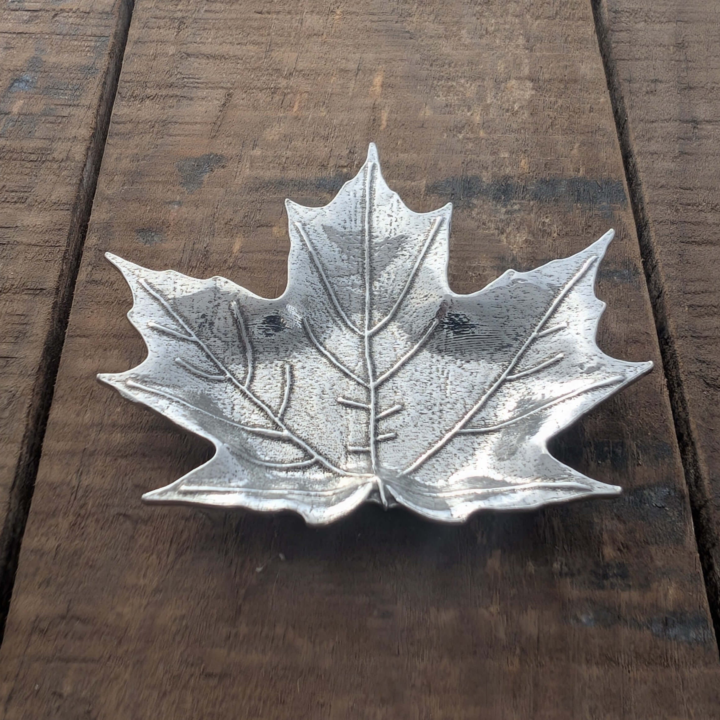 Pewter maple leaf dish on wood surface