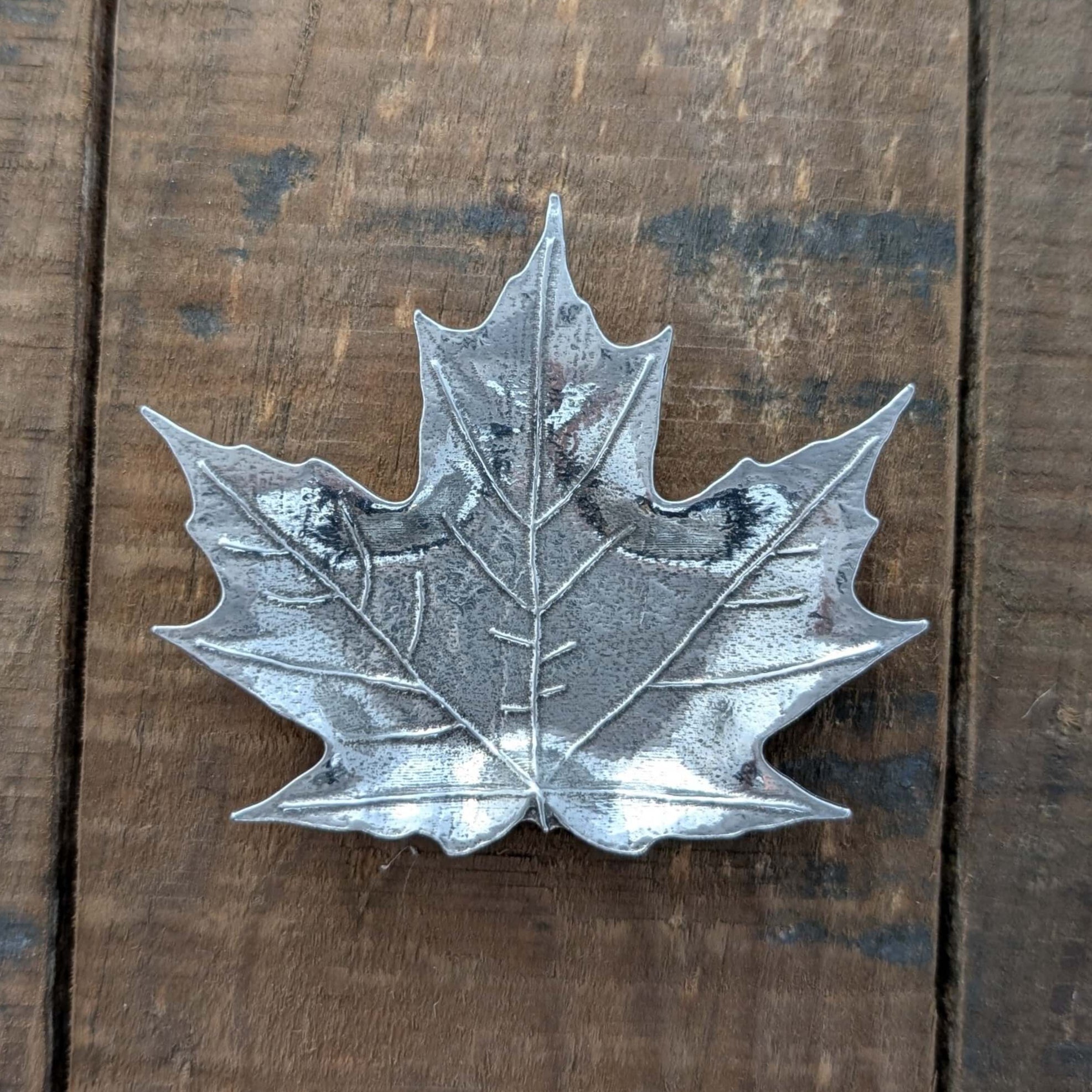 Pewter maple leaf dish on wood surface