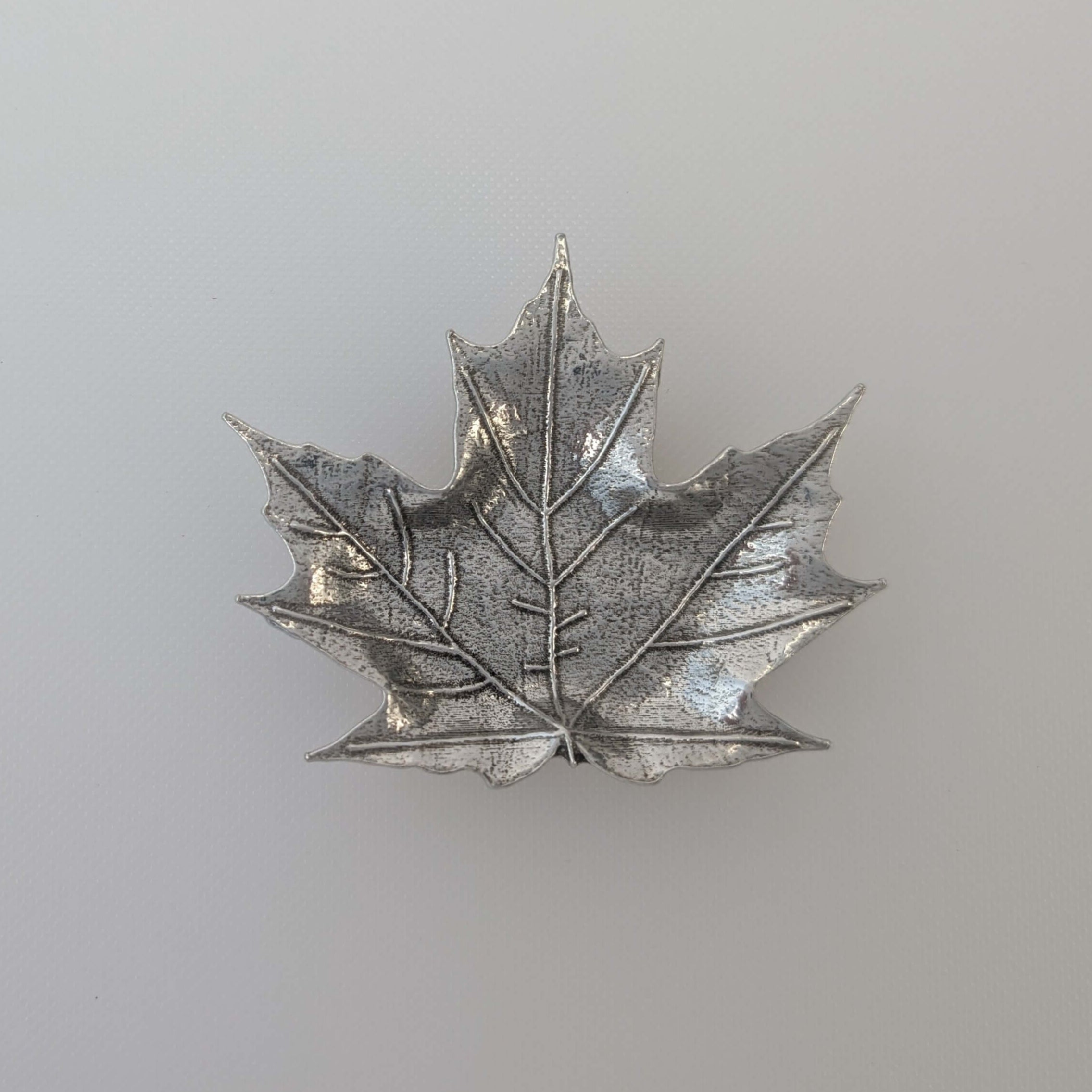 Pewter maple leaf dish on wood surface