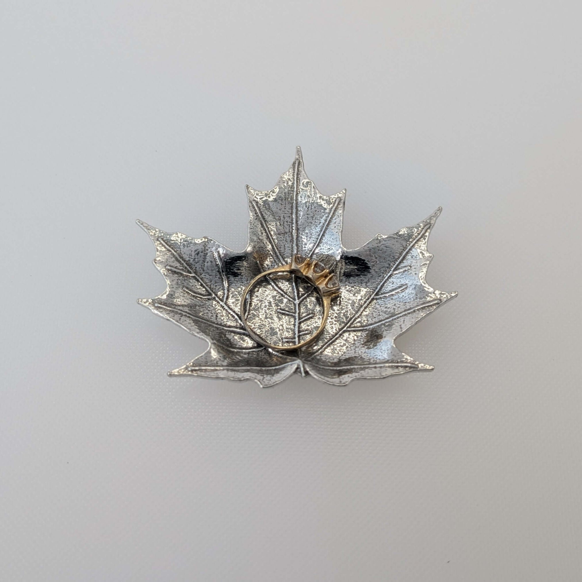Pewter maple leaf dish on wood surface