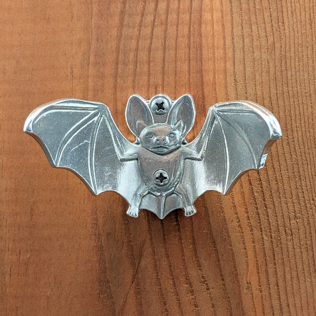 Pewter bat wall hook mounted on a wood board, front view with wings spread